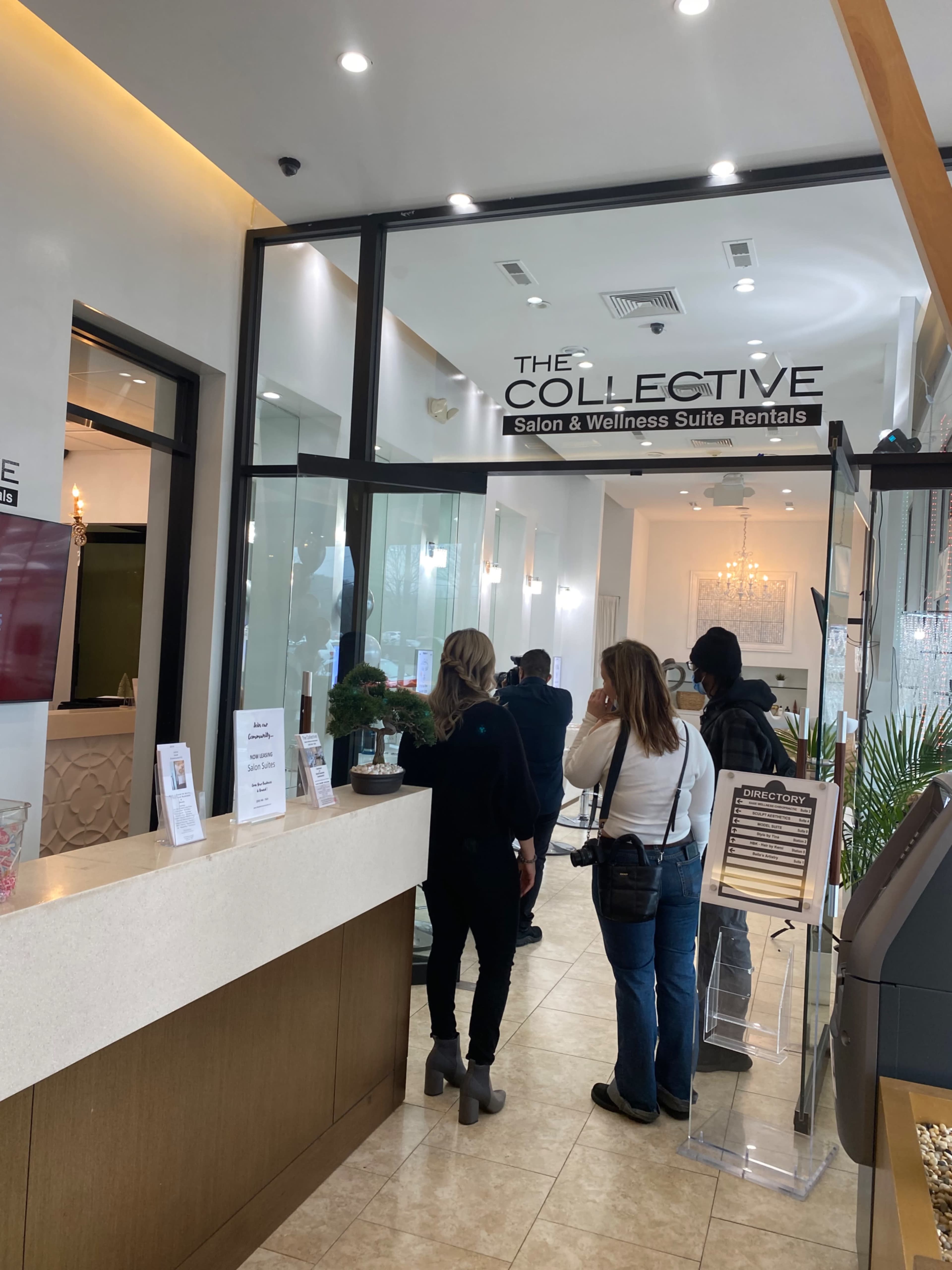 A group of people stands in line at the reception area of a wellness and salon suite rental establishment.