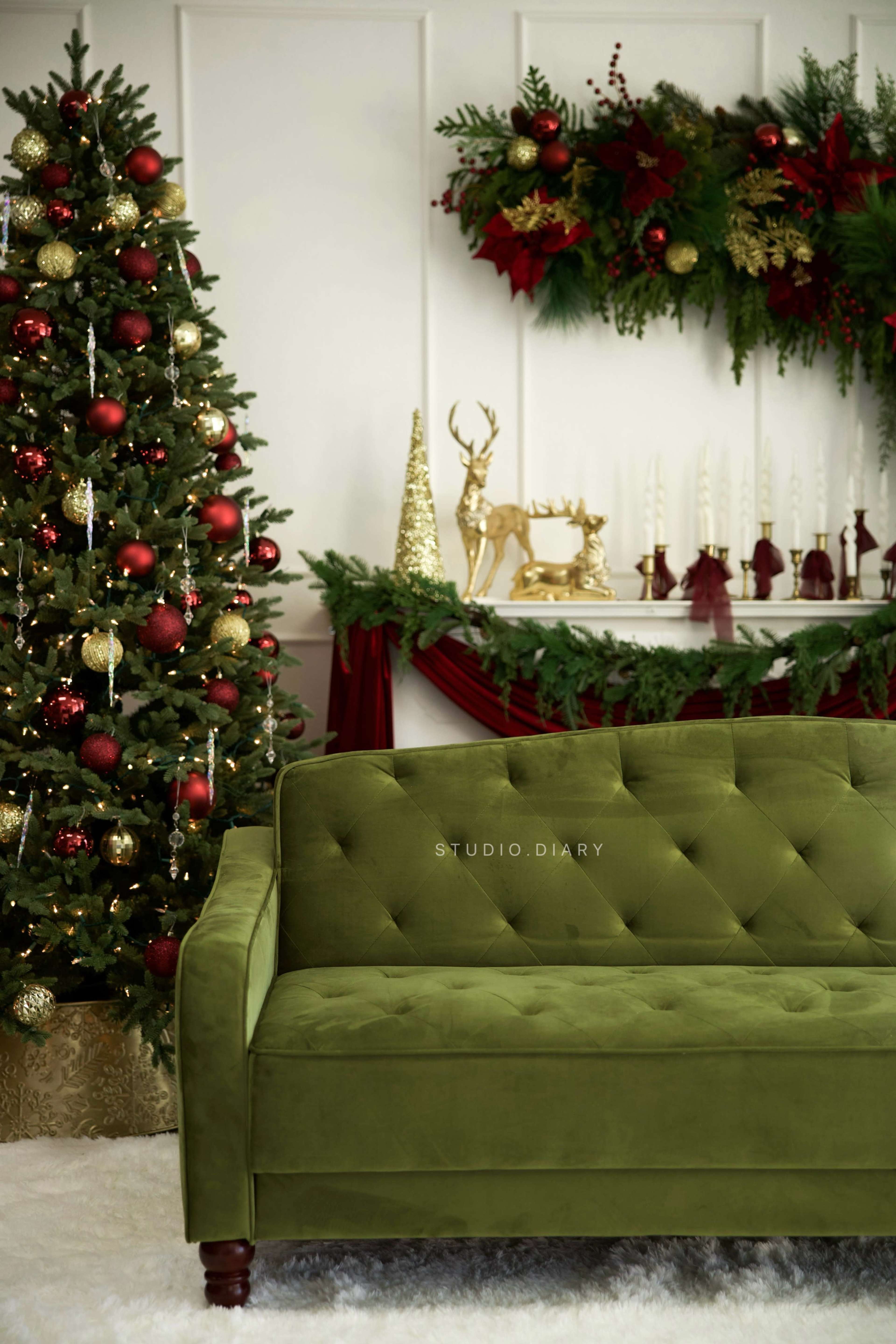 The image features a green tufted sofa in front of a decorated Christmas tree and a mantel adorned with festive garlands and ornaments.