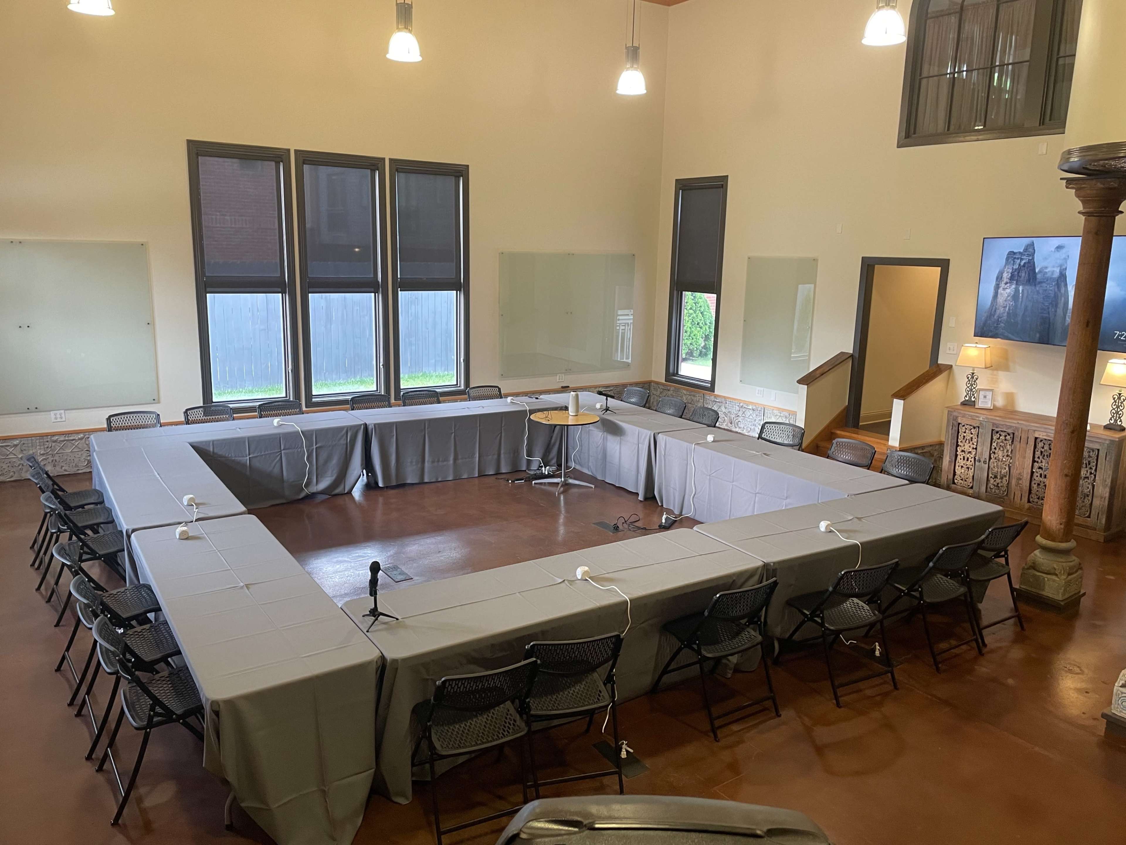 A large meeting room set up with an arrangement of tables and chairs in an open rectangular layout.