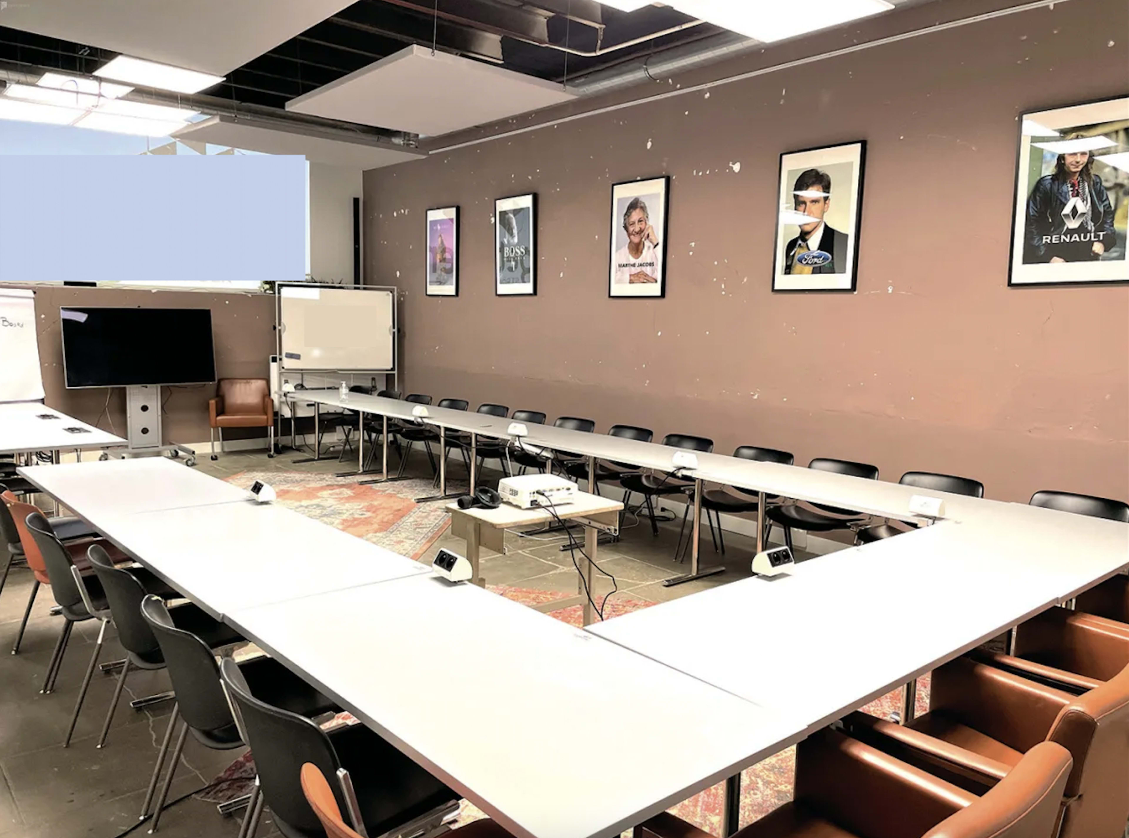 A conference room with a large U-shaped table, chairs around it, and posters on the walls.