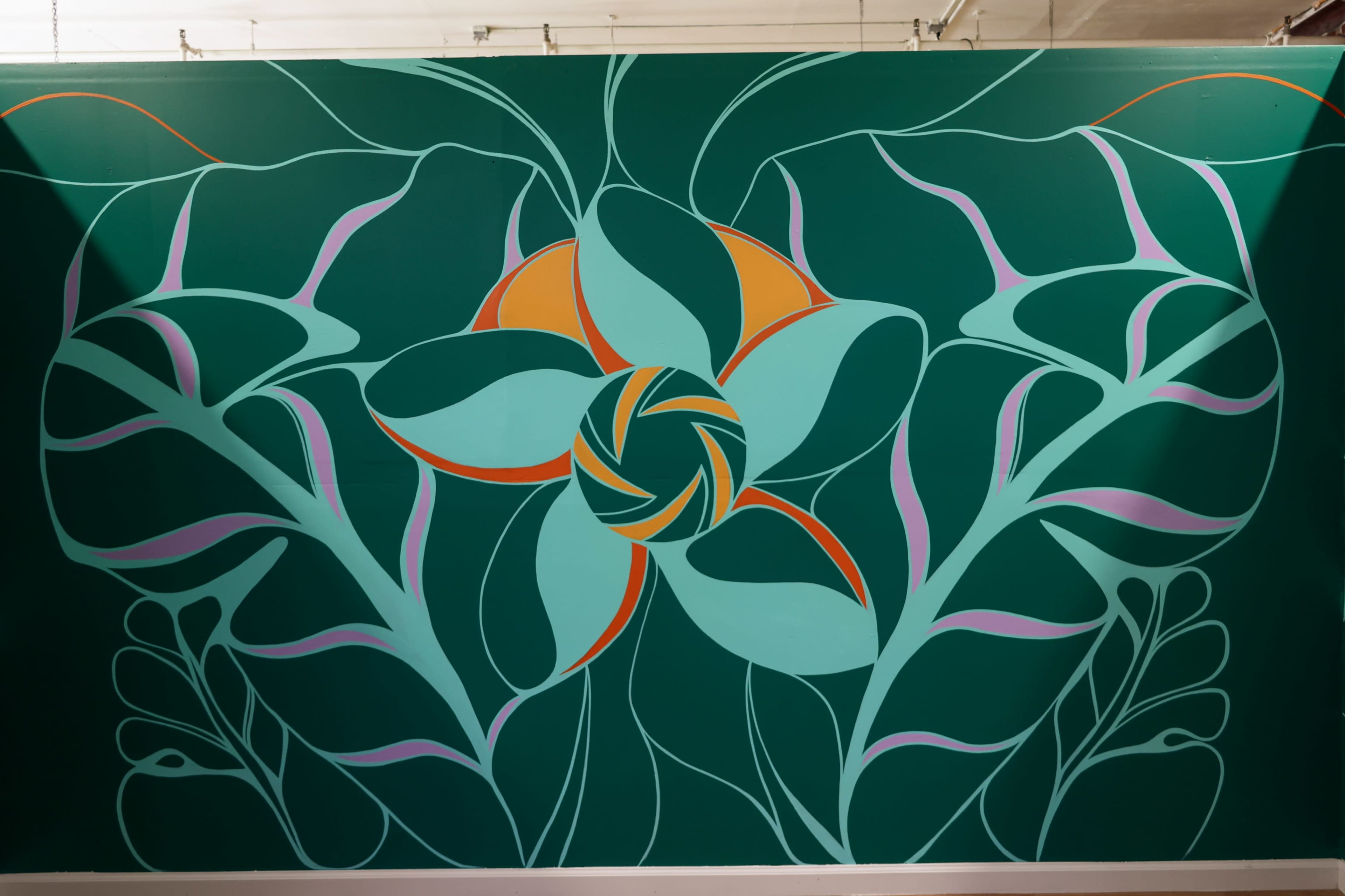 The image features a mural with a large stylized flower in the center, surrounded by green leaves and abstract shapes against a dark green background.