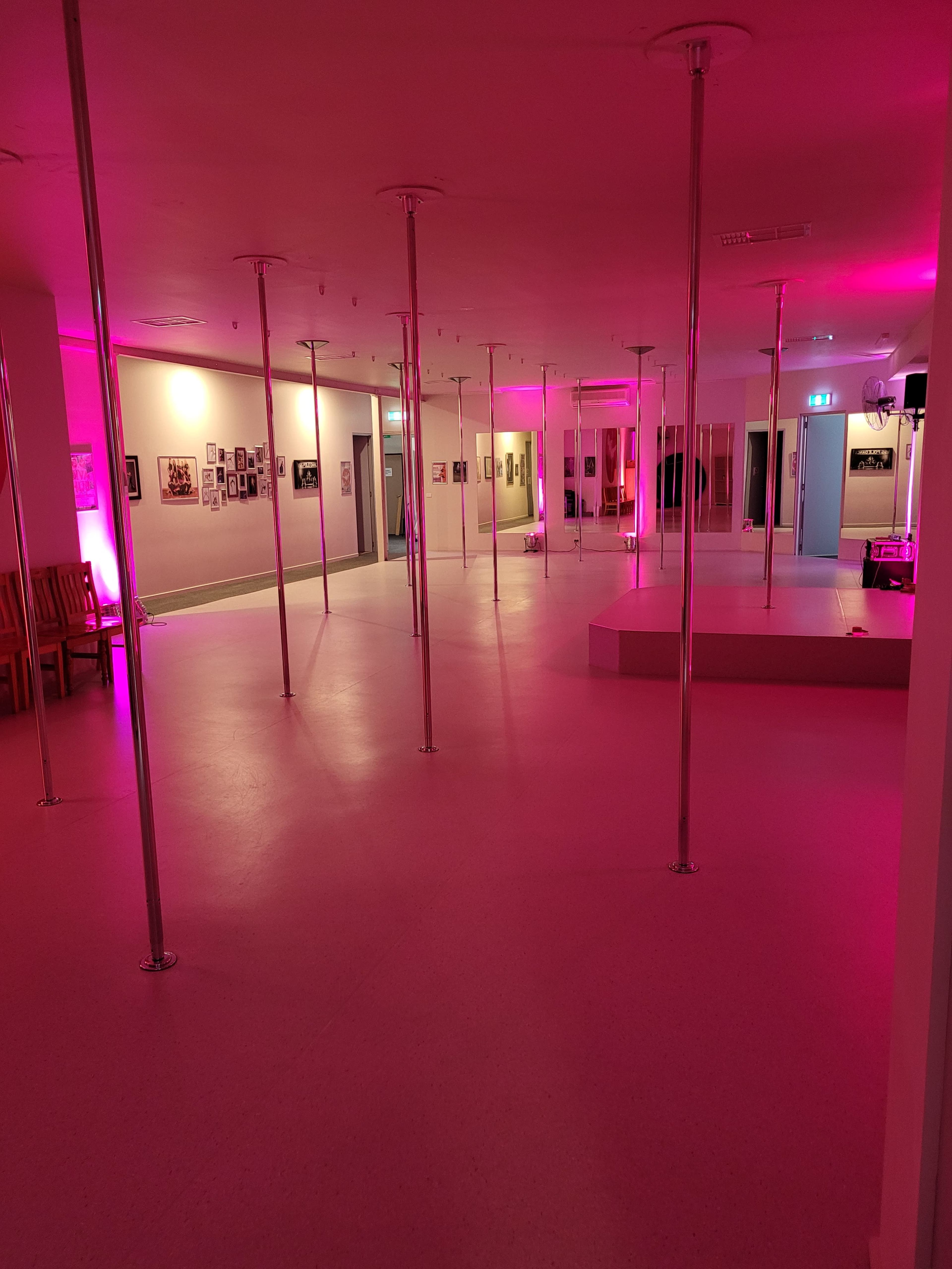 An empty studio space featuring multiple vertical poles and purple lighting.