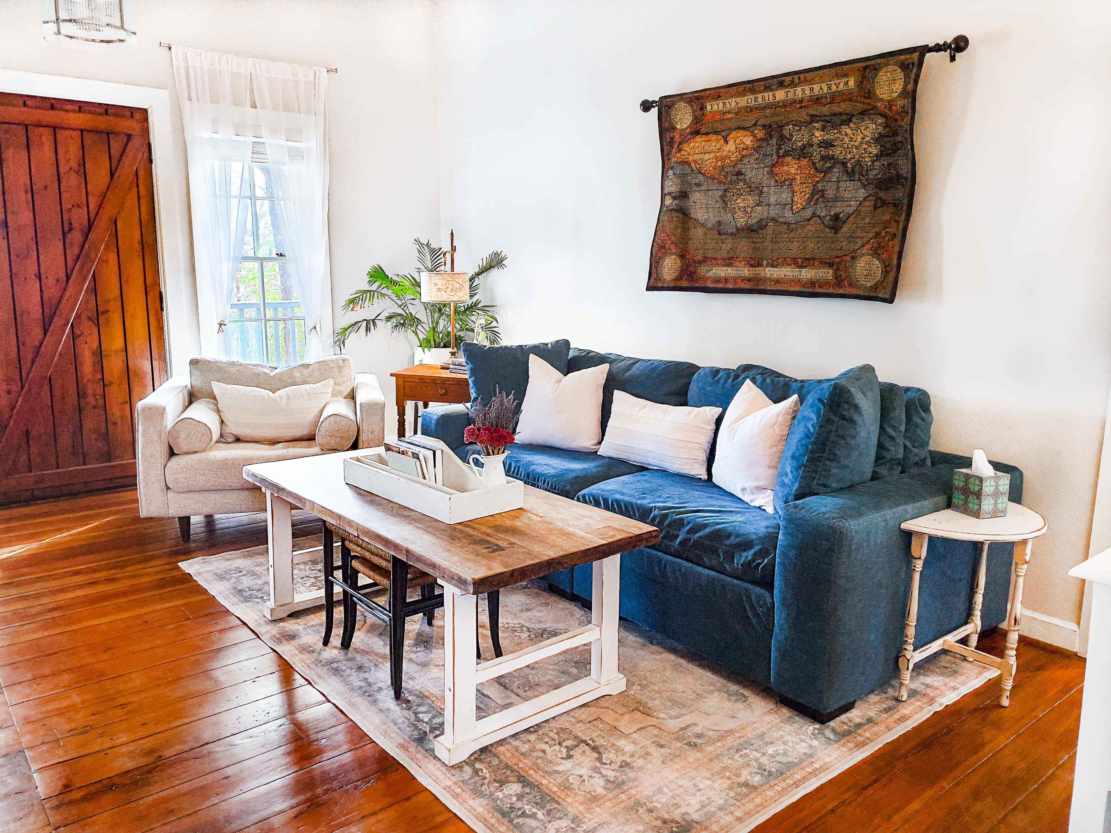 The image features a cozy living room with a blue sofa, a wooden coffee table, and a large world map hanging on the wall.