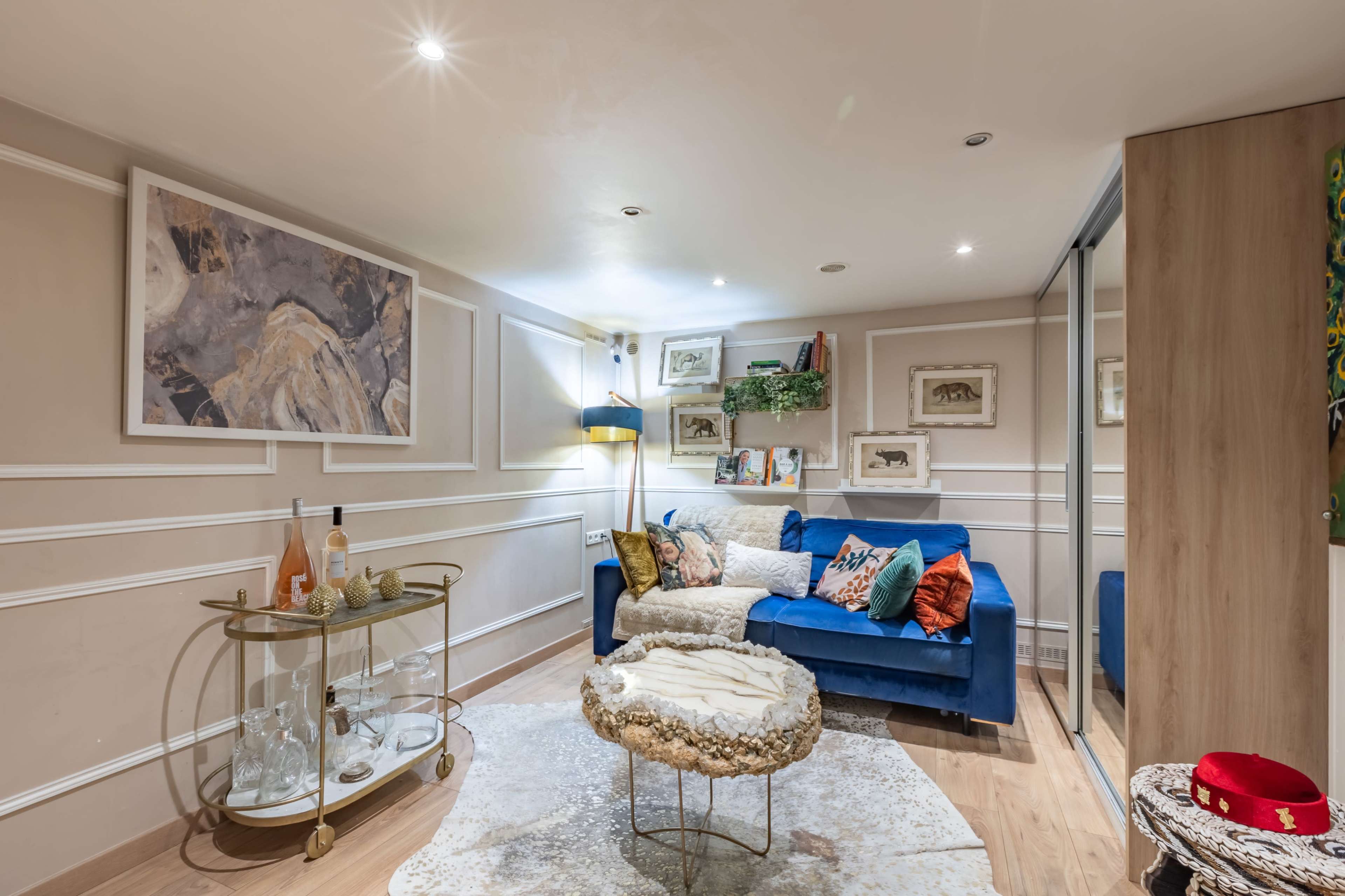 The image features a cozy living room with a blue sofa, a decorative cart, and wall art, illuminated by soft lighting.