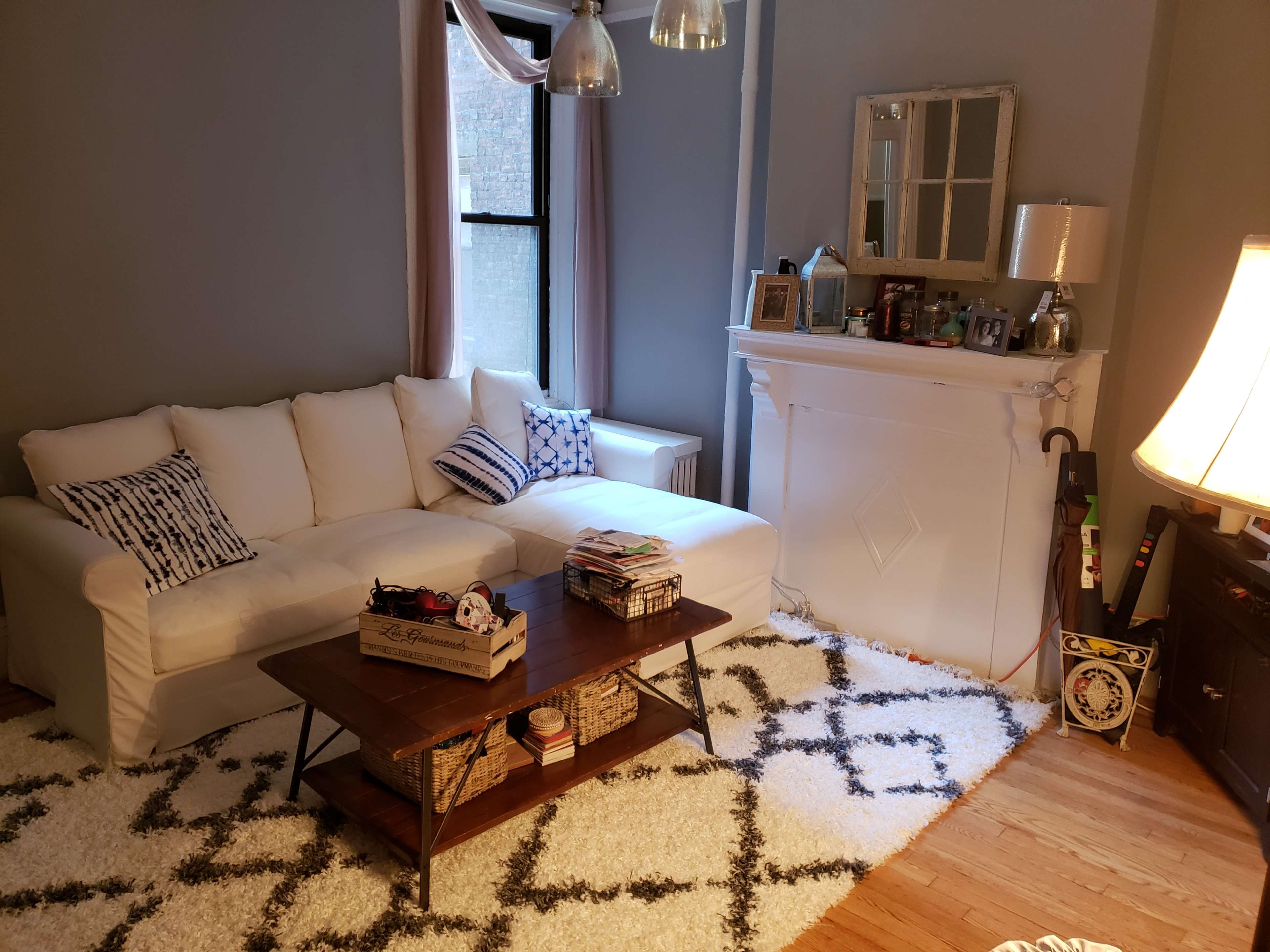 A modern living room with a white sectional sofa, a wooden coffee table, and a rug featuring a geometric pattern on the hardwood floor.