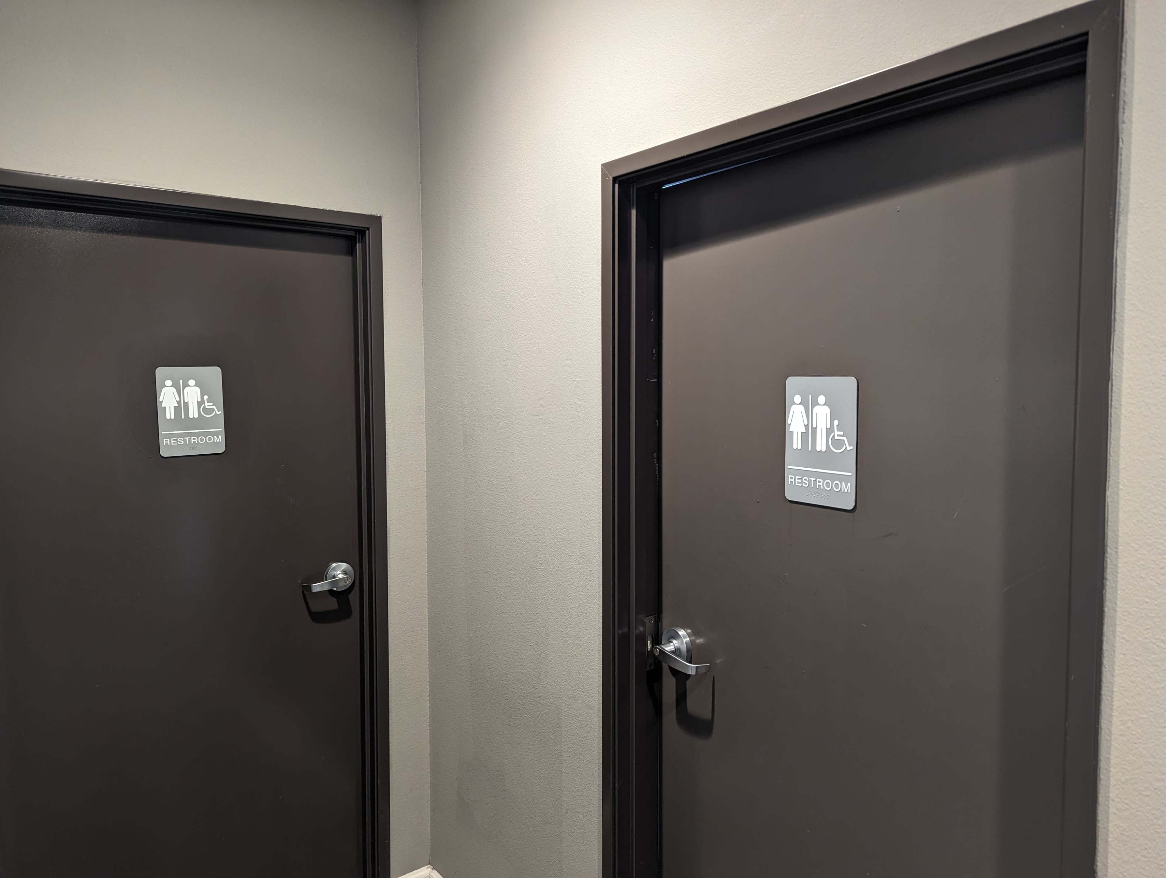 Two restroom doors with signs indicating they are for men's and accessible use, set in a hallway with gray walls.