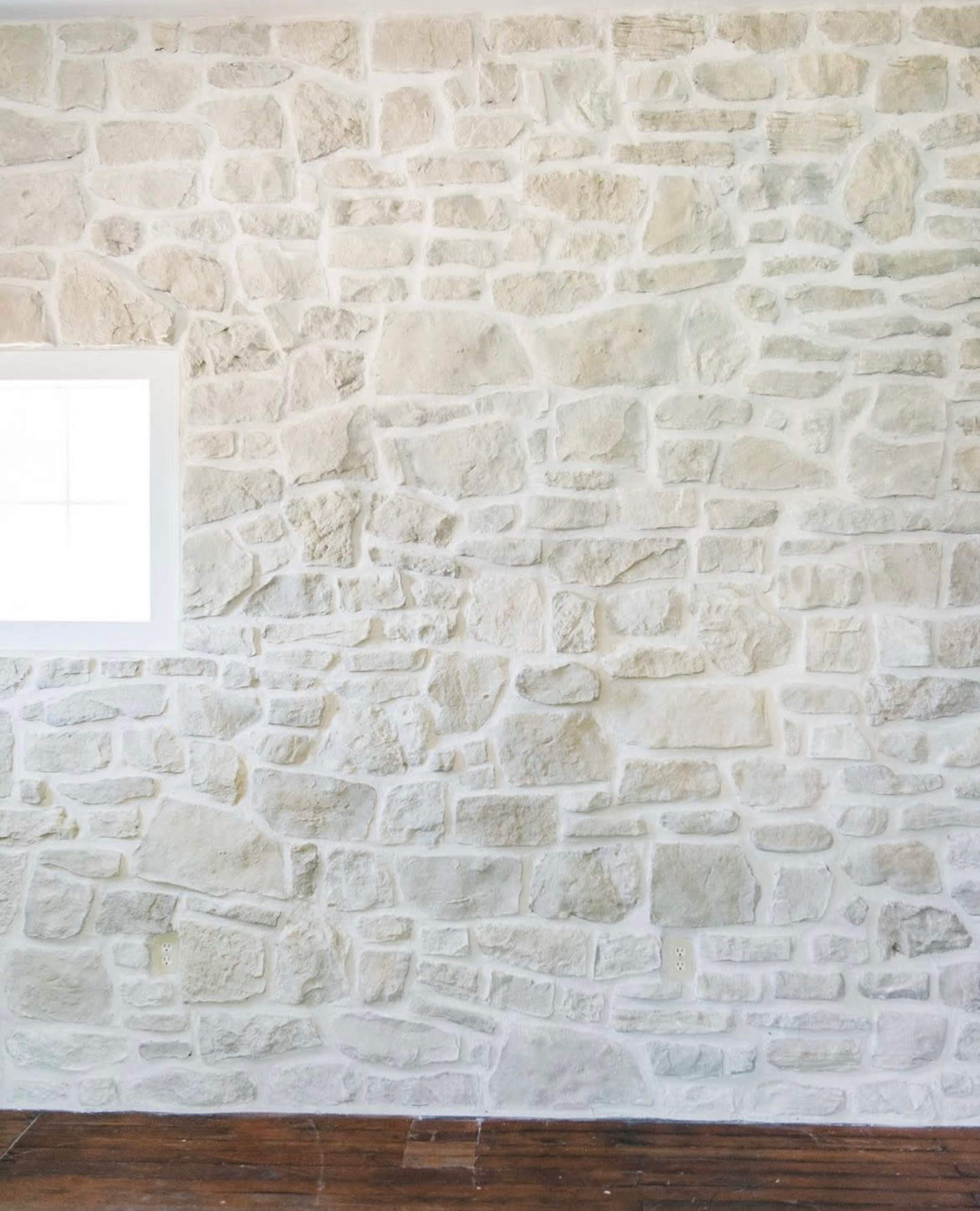 A textured stone wall with a small window on the left side.