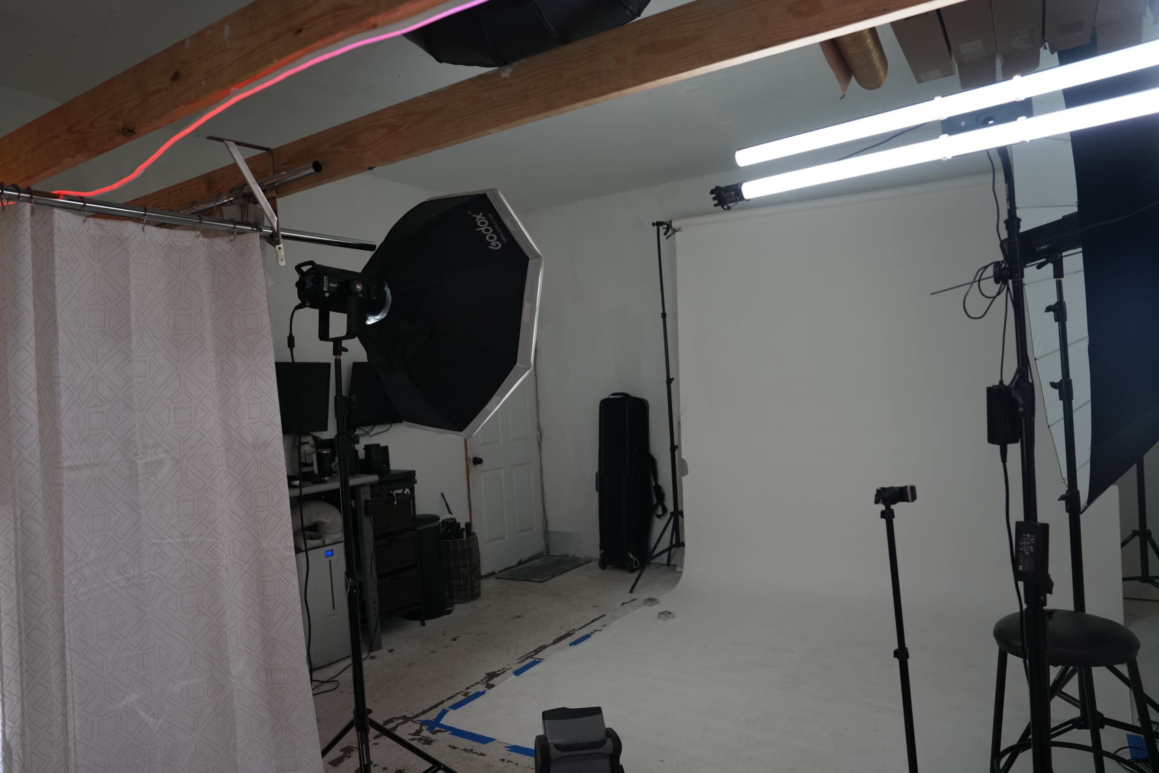 A photography studio setup with various lighting equipment, a backdrop, and a cluttered workspace.