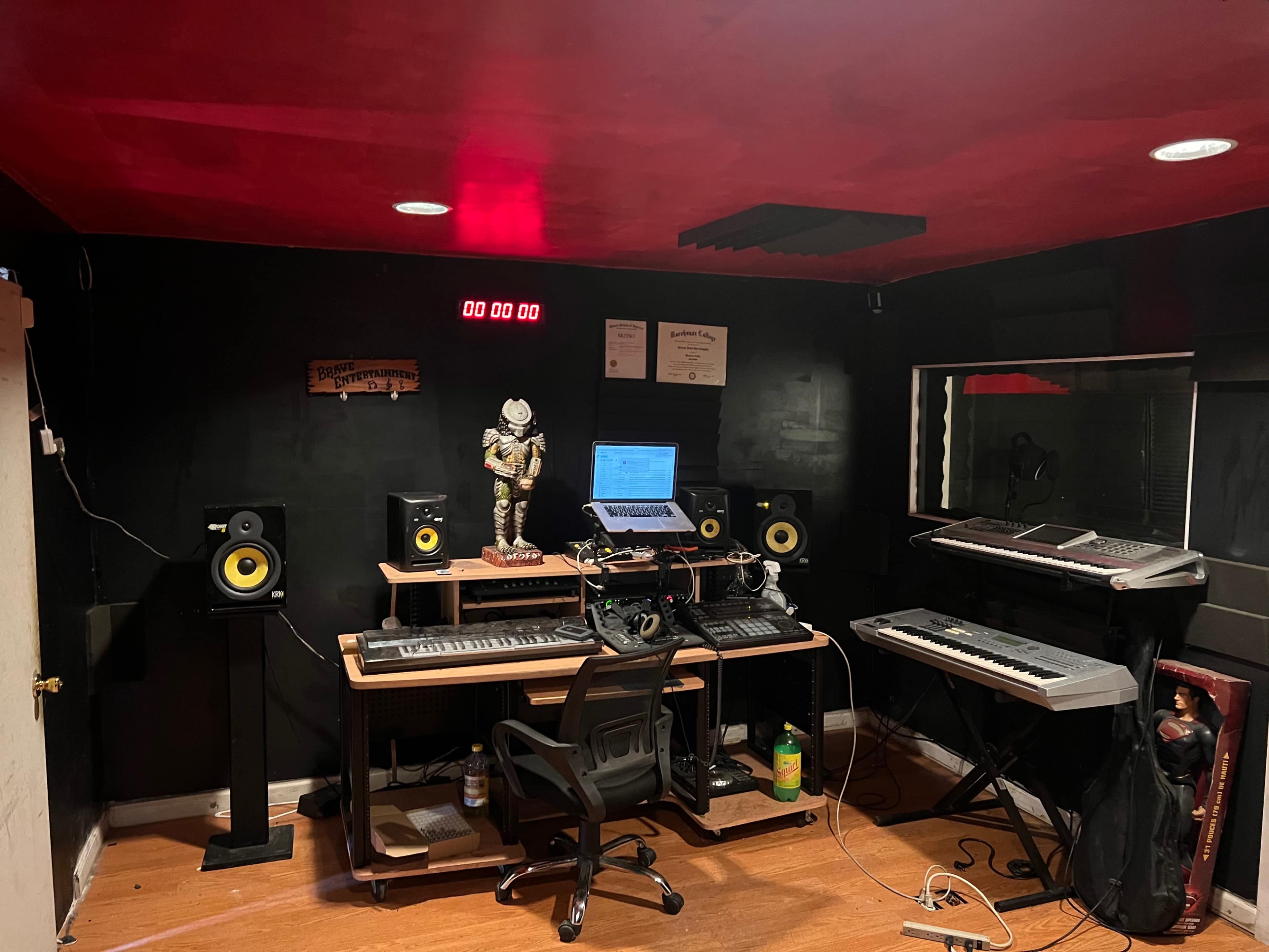 A music production studio equipped with speakers, keyboards, a computer, and a skeleton figurine on the desk.