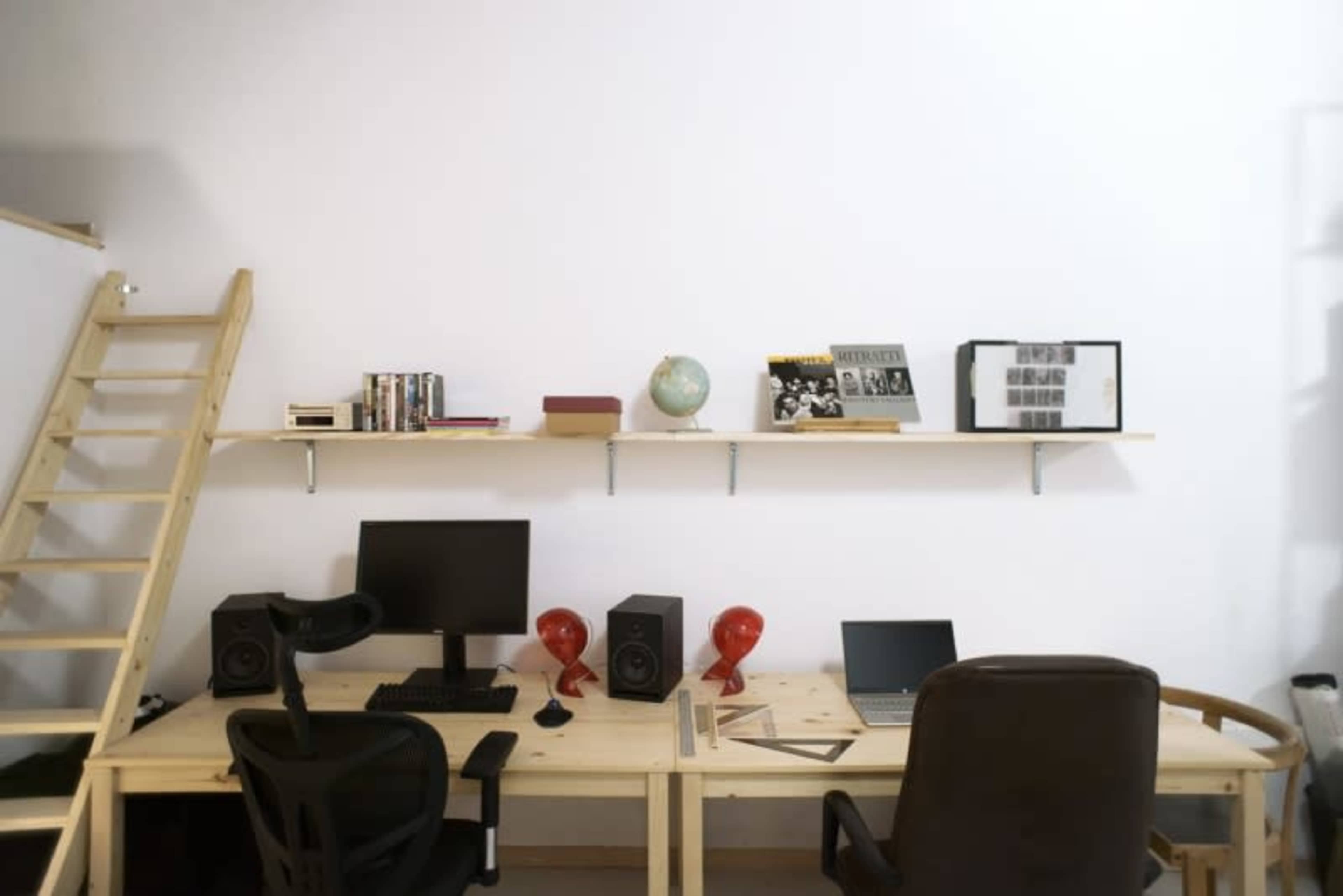A minimalist workspace featuring two desks, a shelf with books and decor items, and a wooden ladder against a white wall.