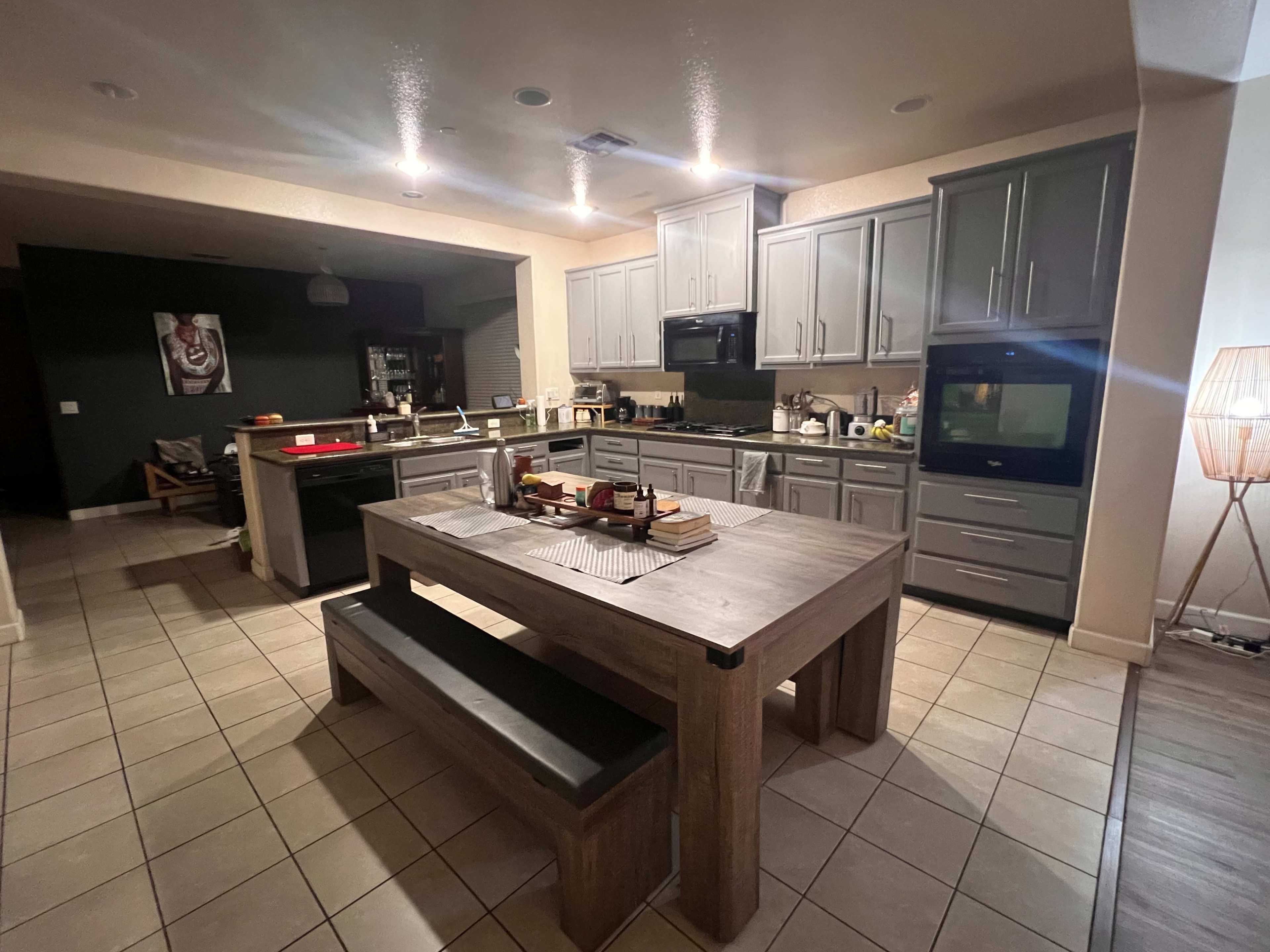A modern kitchen and dining area with a wooden table, gray cabinets, and various kitchen appliances.