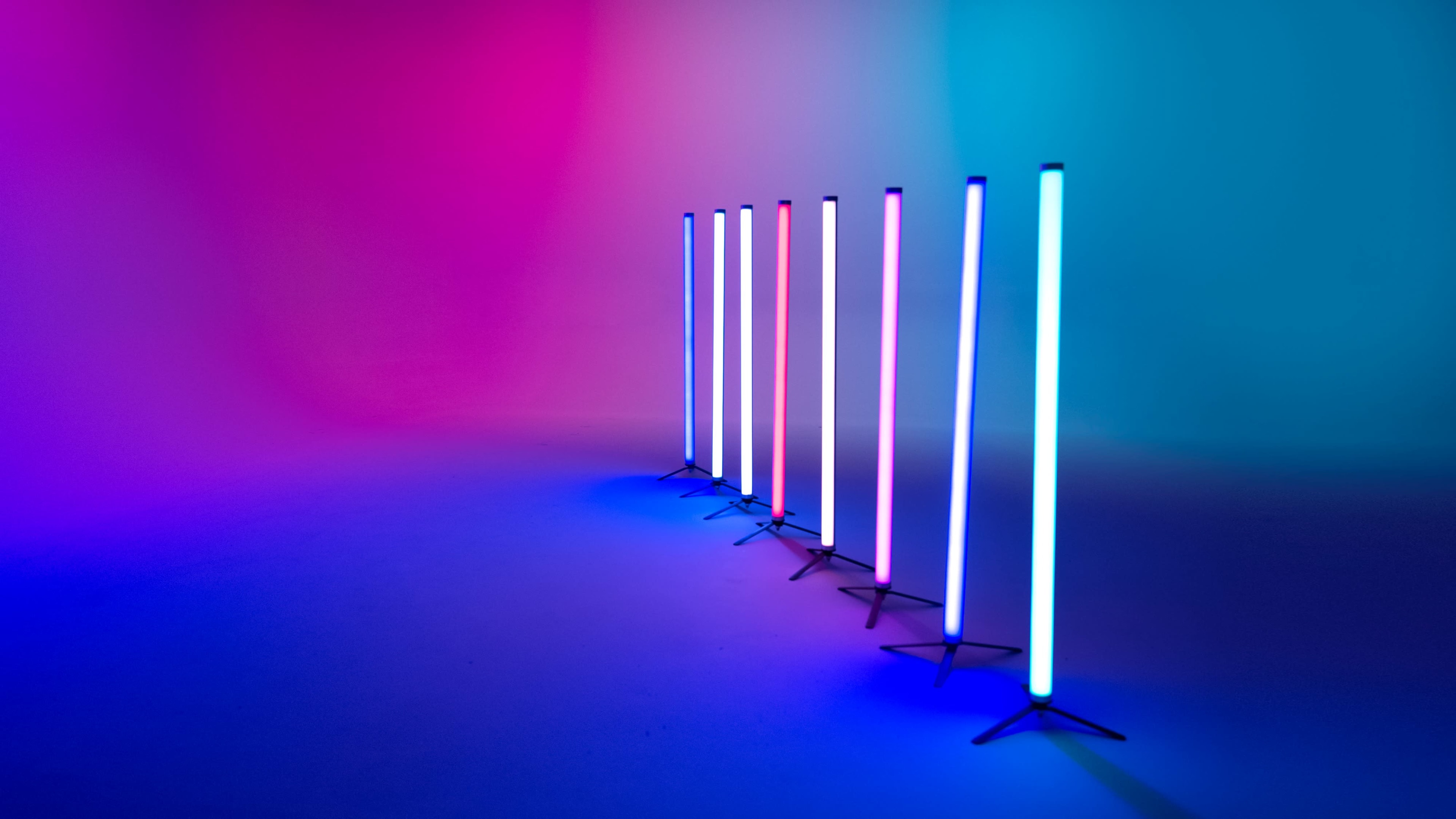 A row of illuminated vertical light tubes in varying colors against a gradient backdrop.