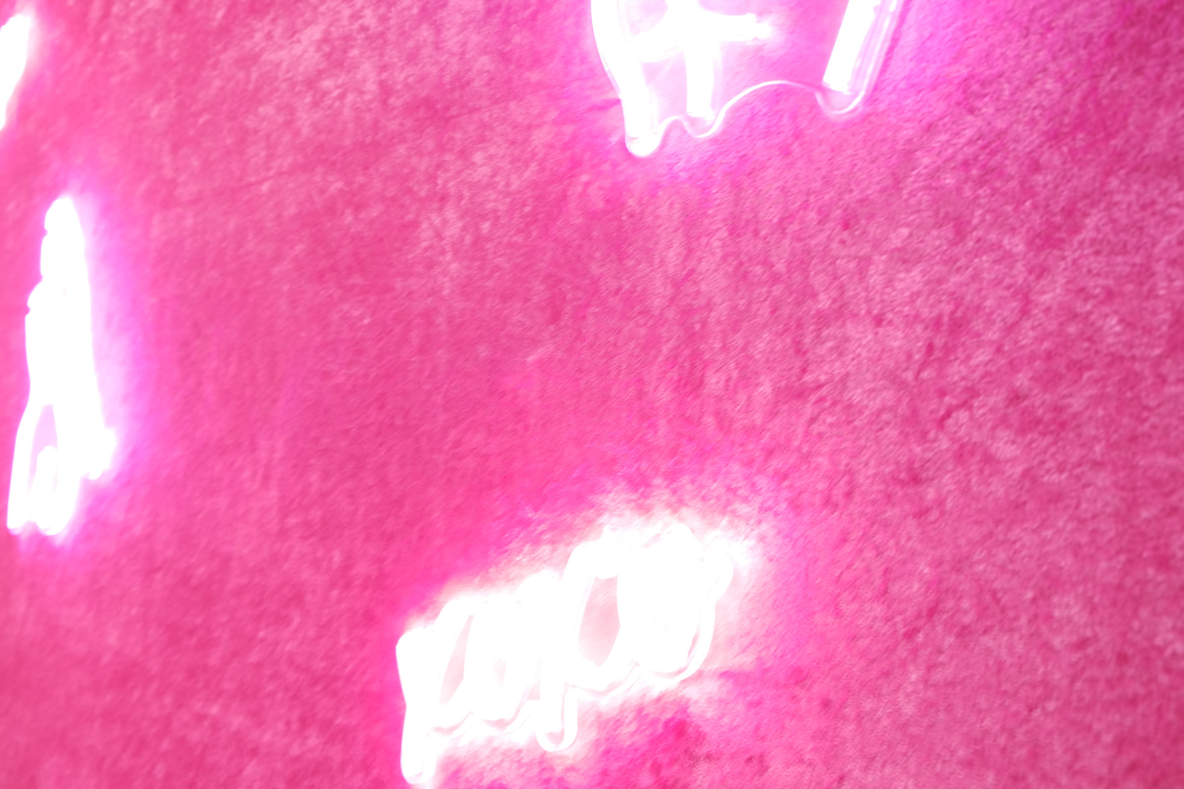 Neon signs in various shapes glowing against a pink wall.