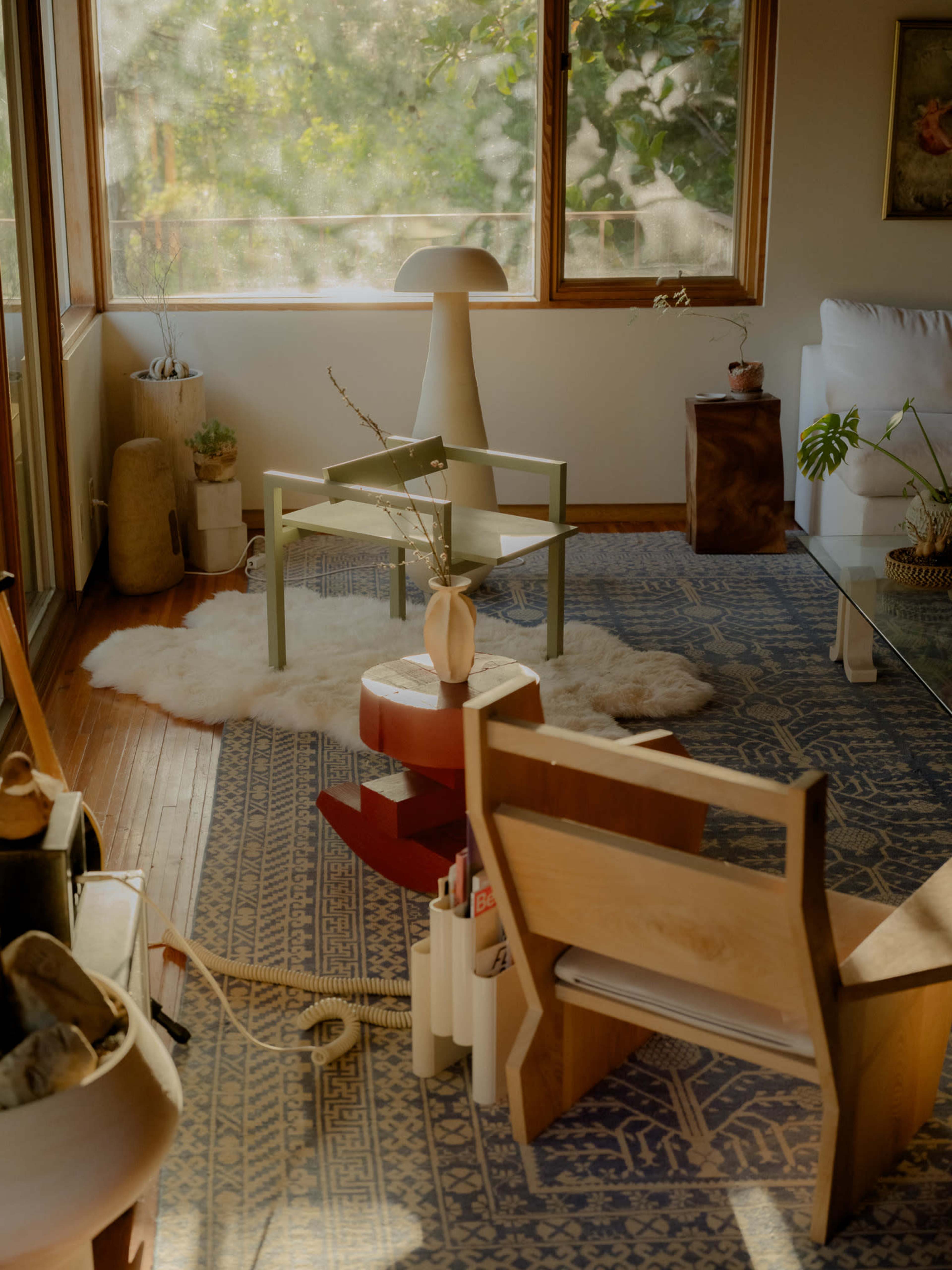 The image depicts a sunlit room with modern furniture, featuring a green chair, a white lamp, a wooden side table, and a decorative rug.
