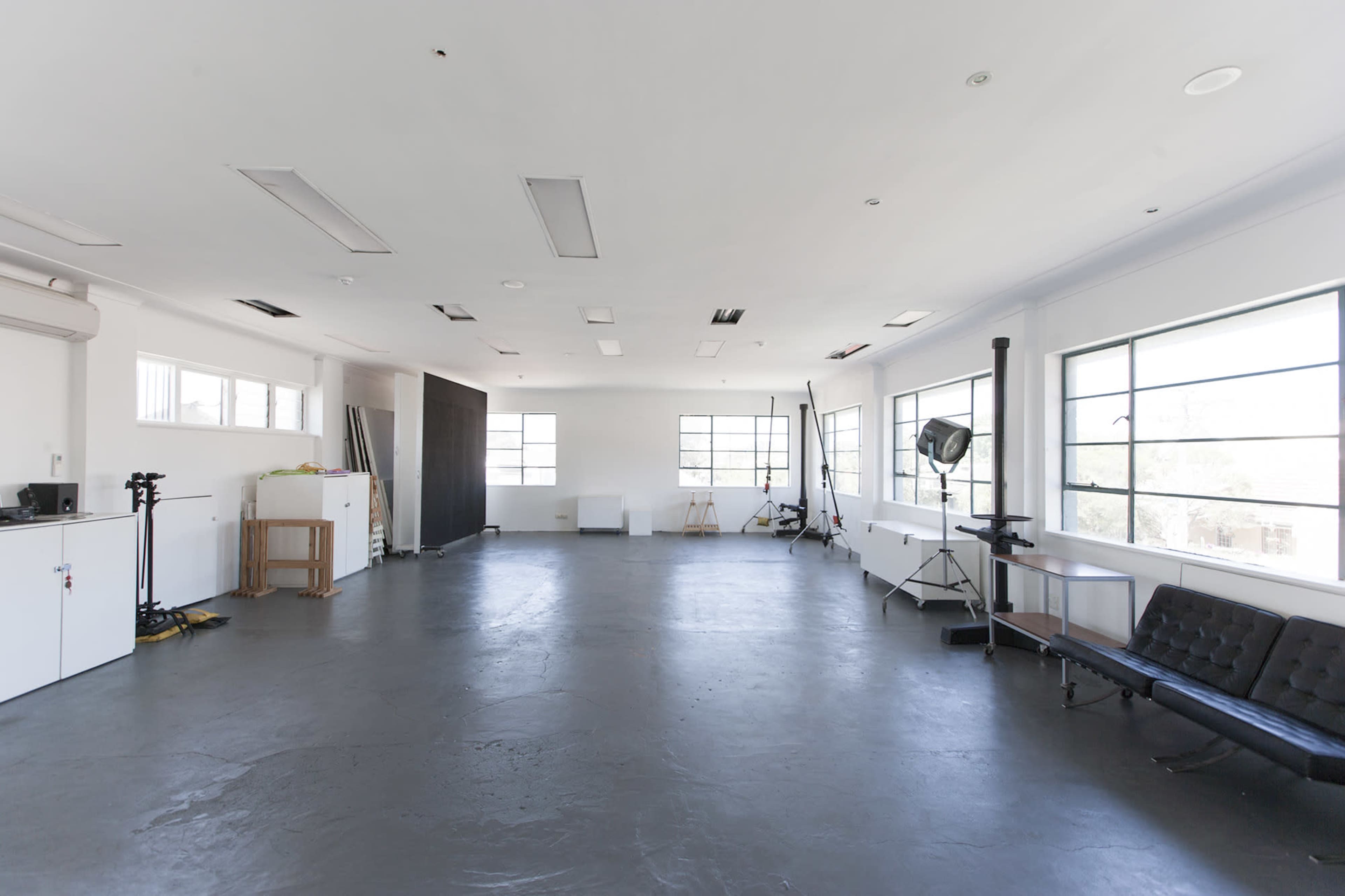 An empty studio space with a polished concrete floor, large windows, and minimal furniture.