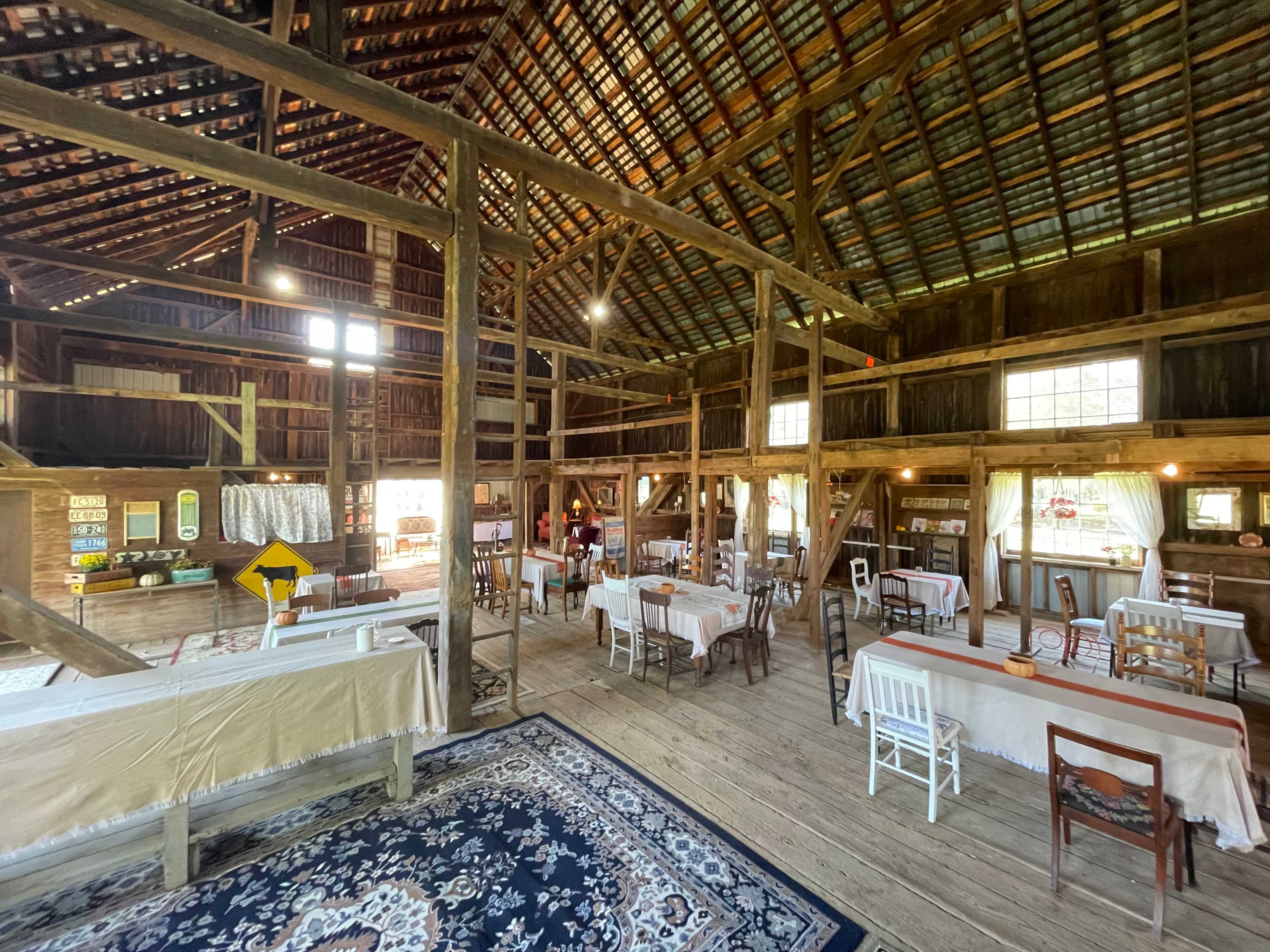 The interior of a spacious wooden barn with tables set for dining and rustic decor.