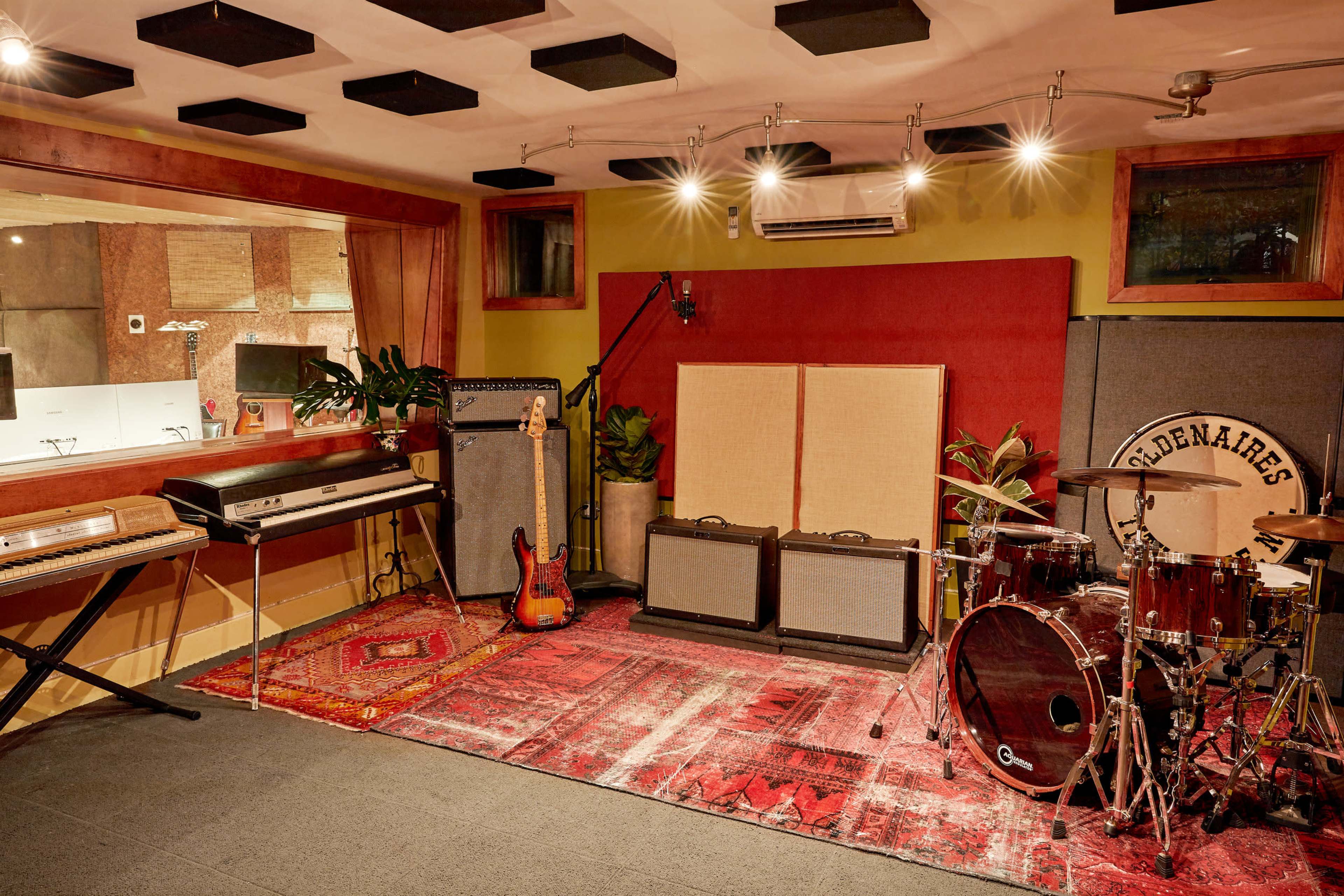 A music recording studio featuring instruments, amplifiers, and sound-absorbing panels on the walls.