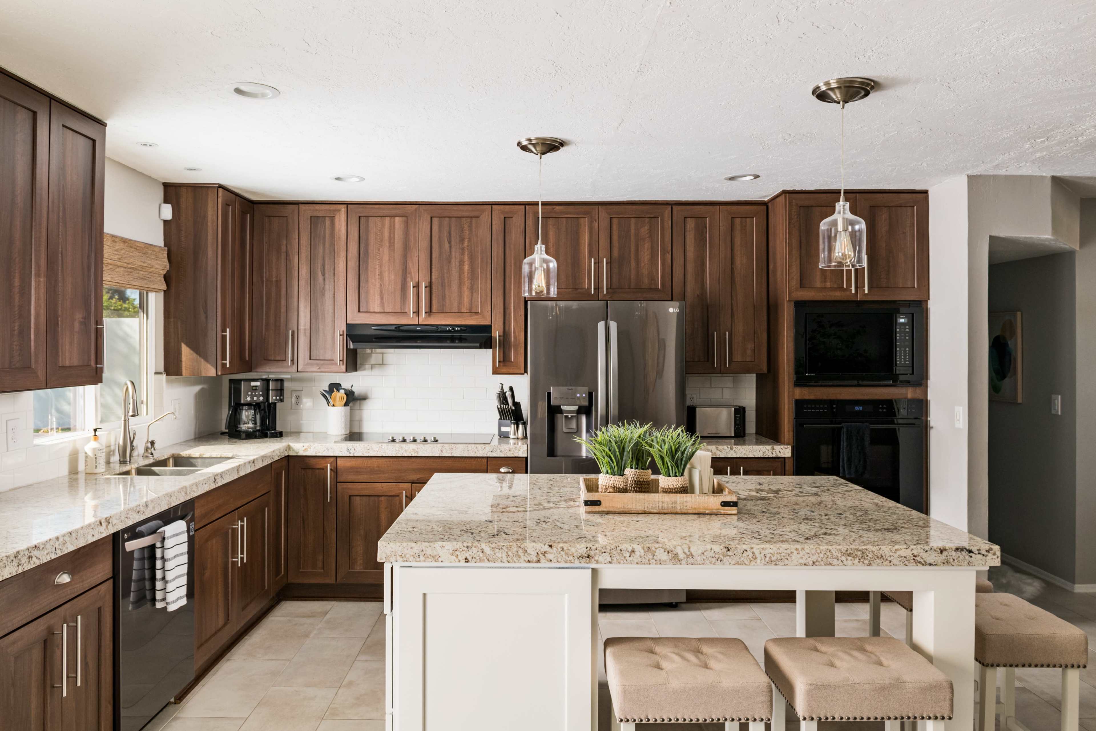 The kitchen features dark wooden cabinets, a large island with a granite countertop, and modern appliances.