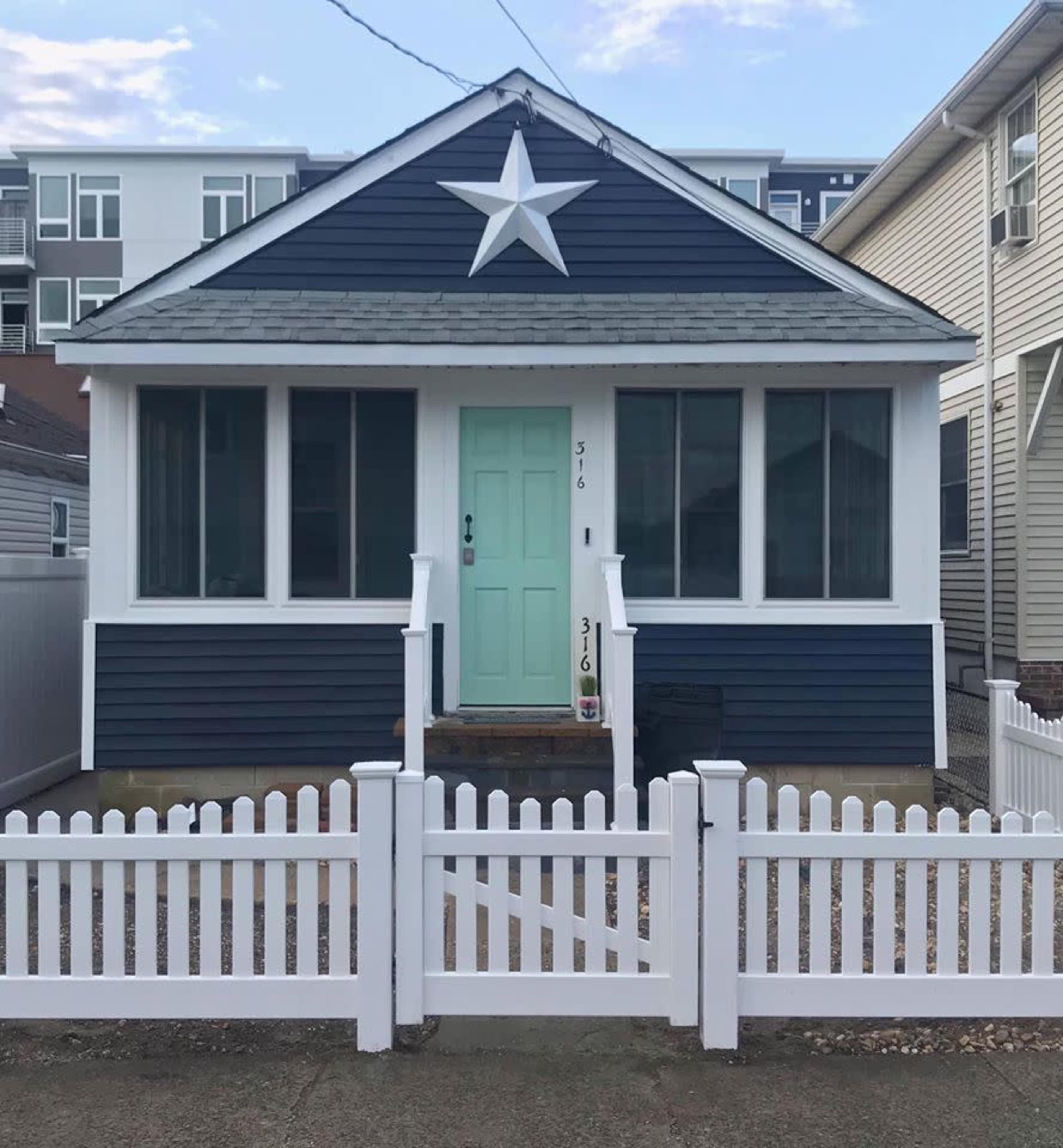 A blue and white house with a large star decoration above the front door and a white picket fence.