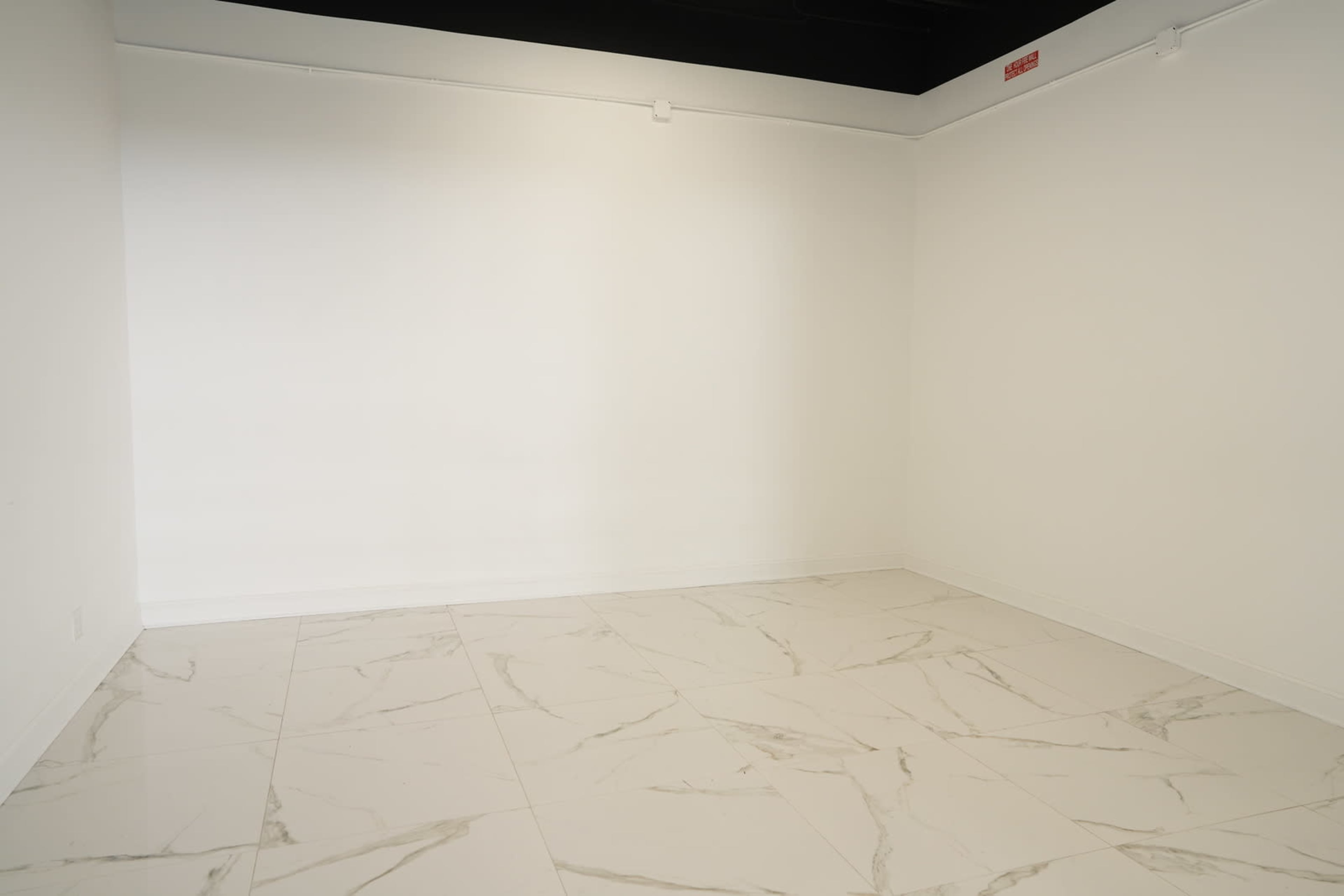 A sparse, empty room with white walls and marble-patterned tile flooring.
