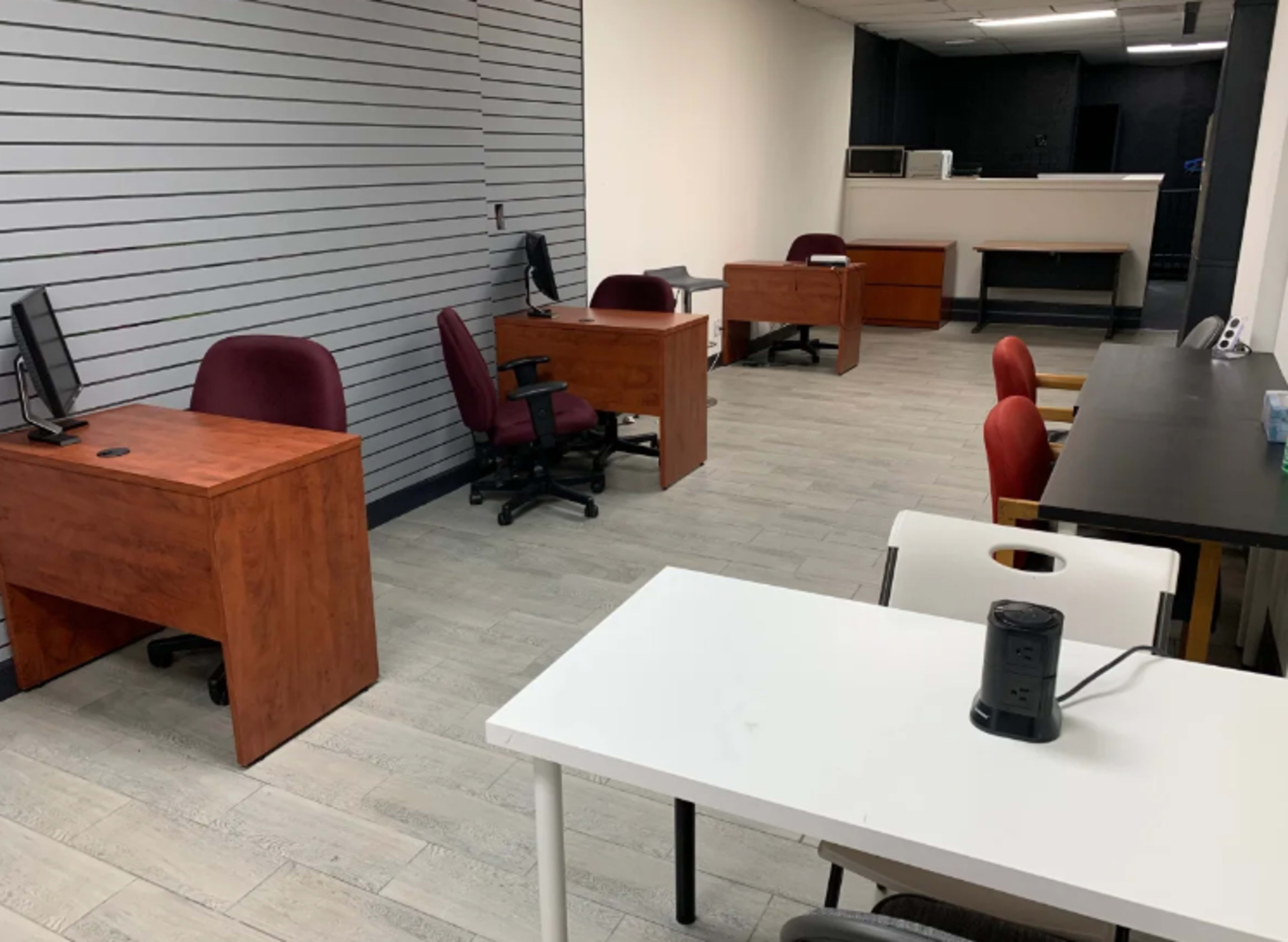 A spacious office interior with several wooden desks, ergonomic chairs, and minimalist decor.