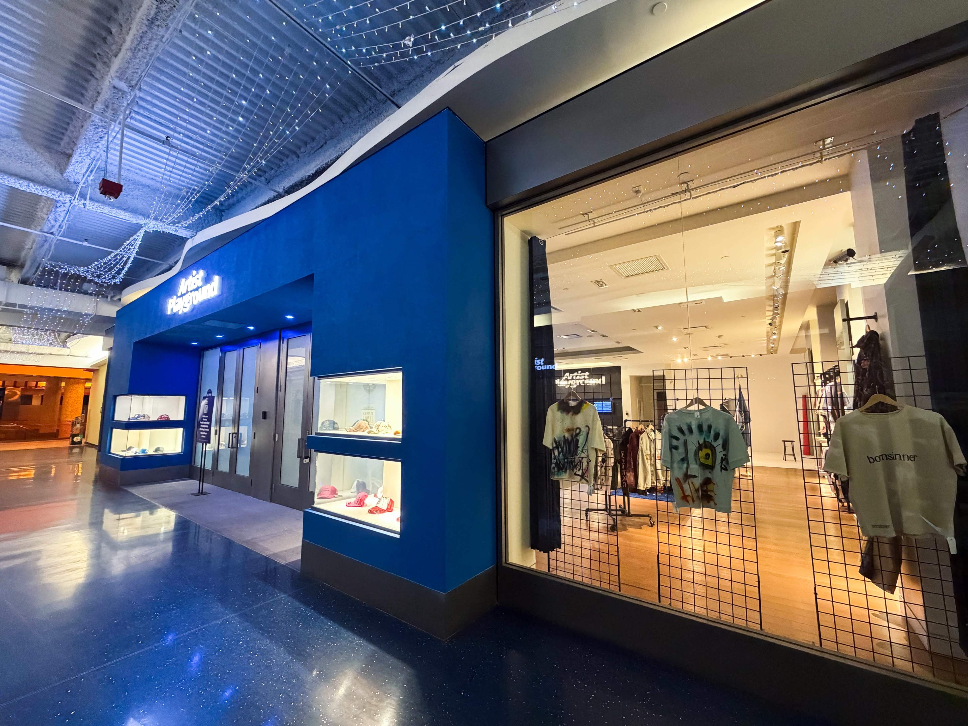 The image shows a retail store entrance with a blue exterior and large windows displaying clothing and accessories inside.