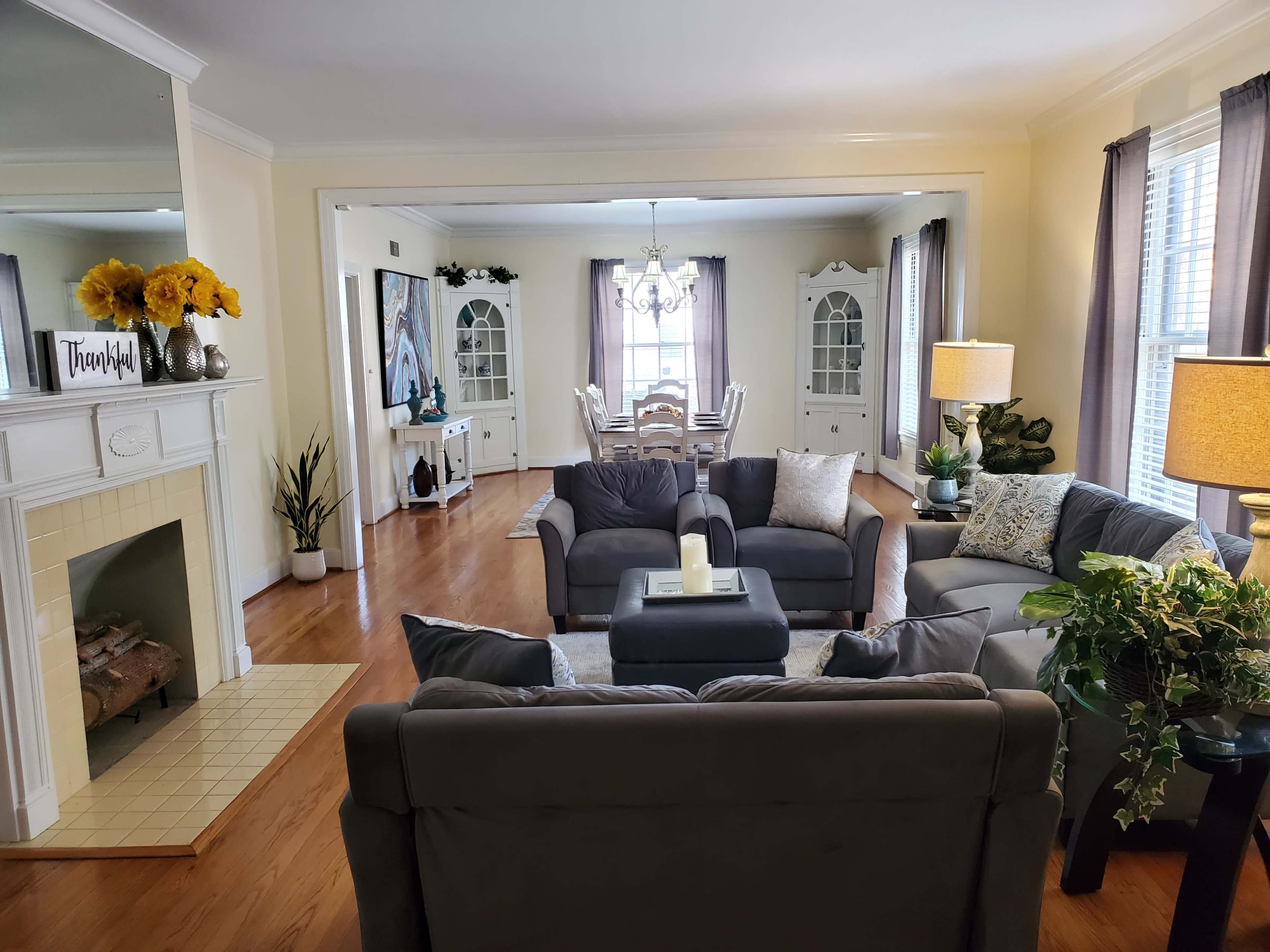 A living room with two gray sofas facing a coffee table, leading to a dining area visible through an open archway.