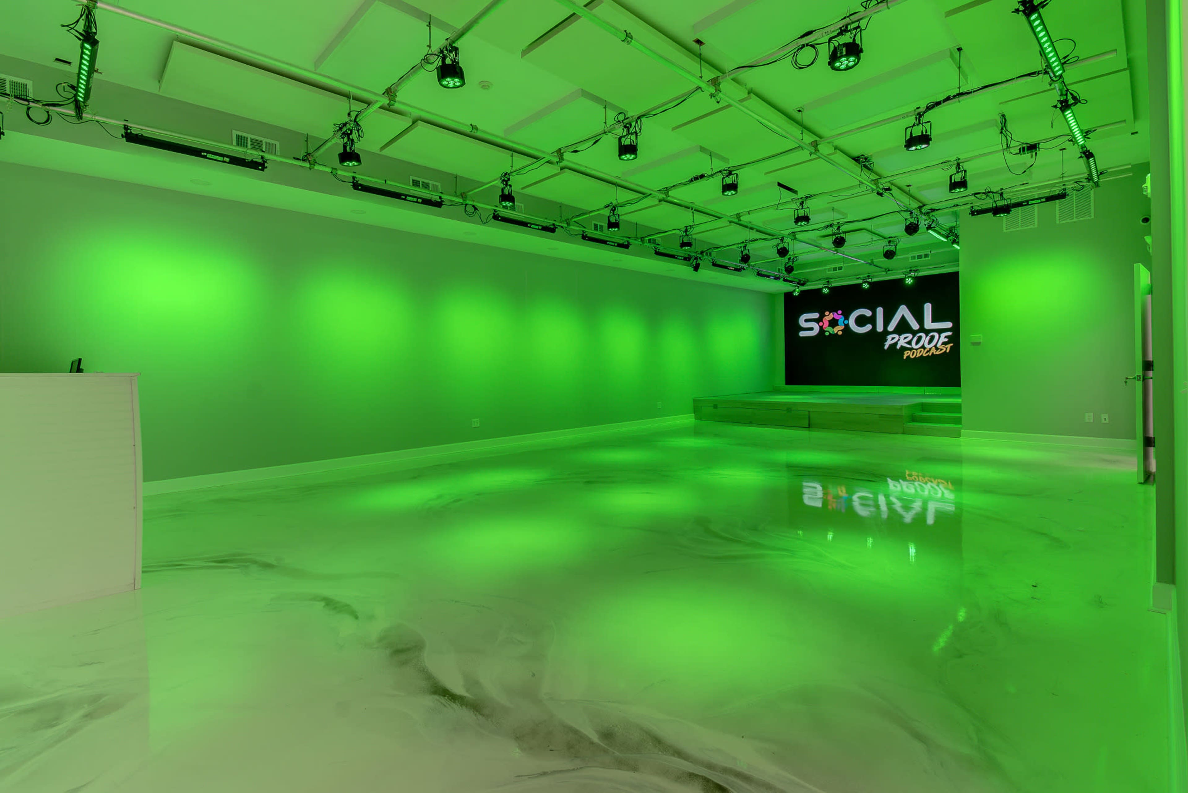 The image shows a modern studio space with green lighting, a glossy marbled floor, and a backdrop displaying the words "SOCIAL PRO."