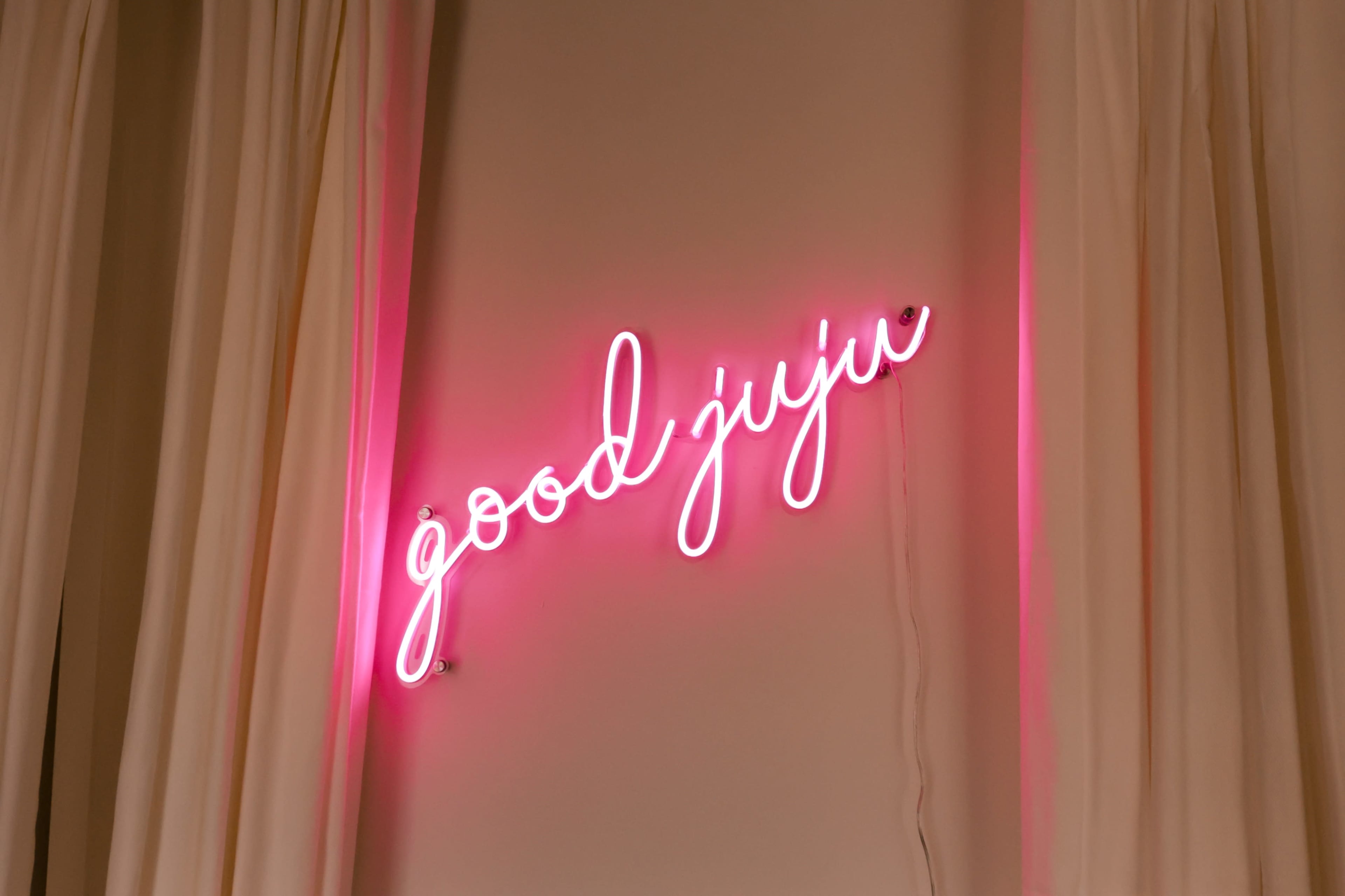 A pink neon sign displaying the words "good juju" is illuminated on a wall.