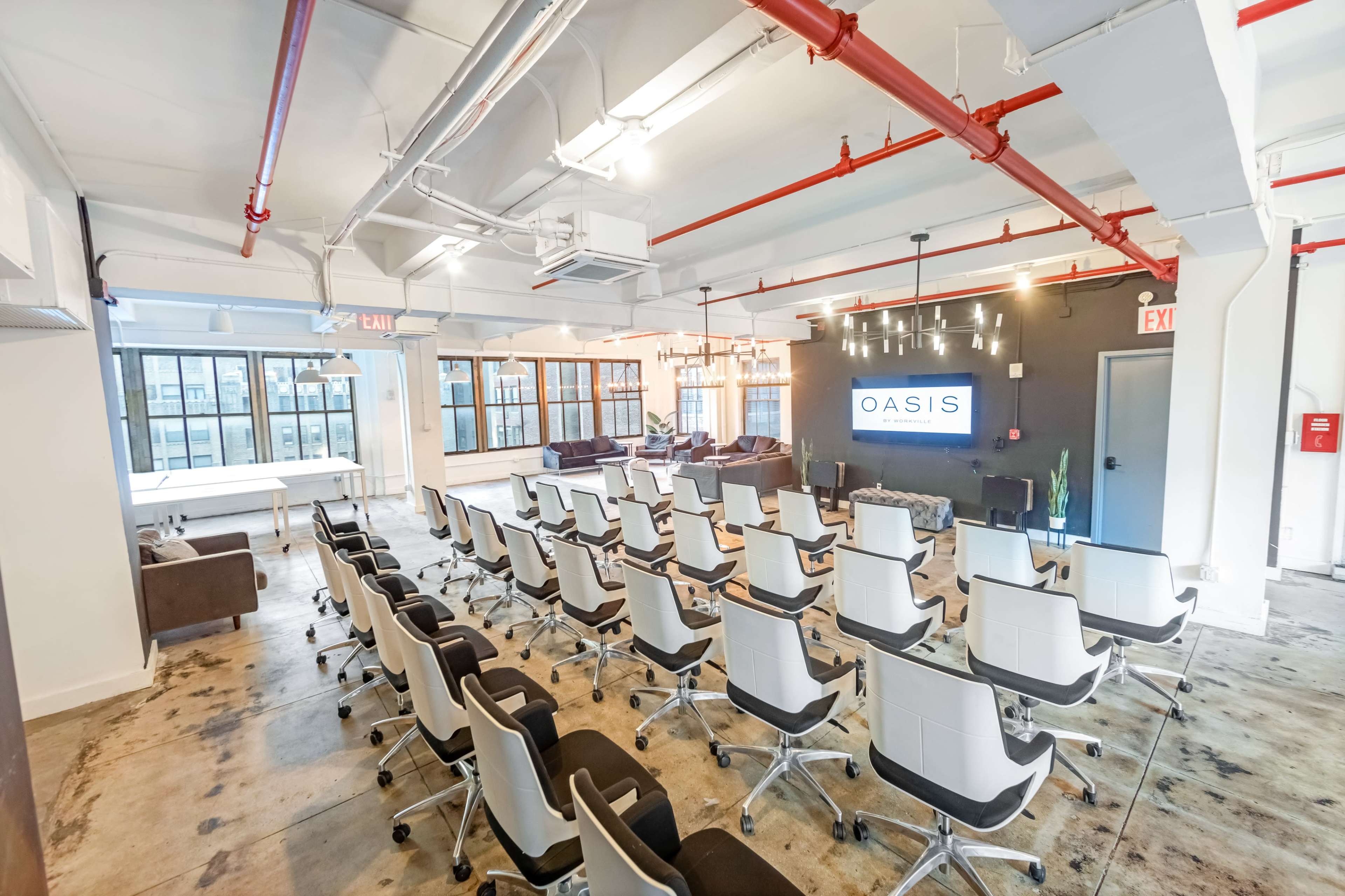A modern conference room with rows of white chairs facing a large screen displaying the logo "OASIS."