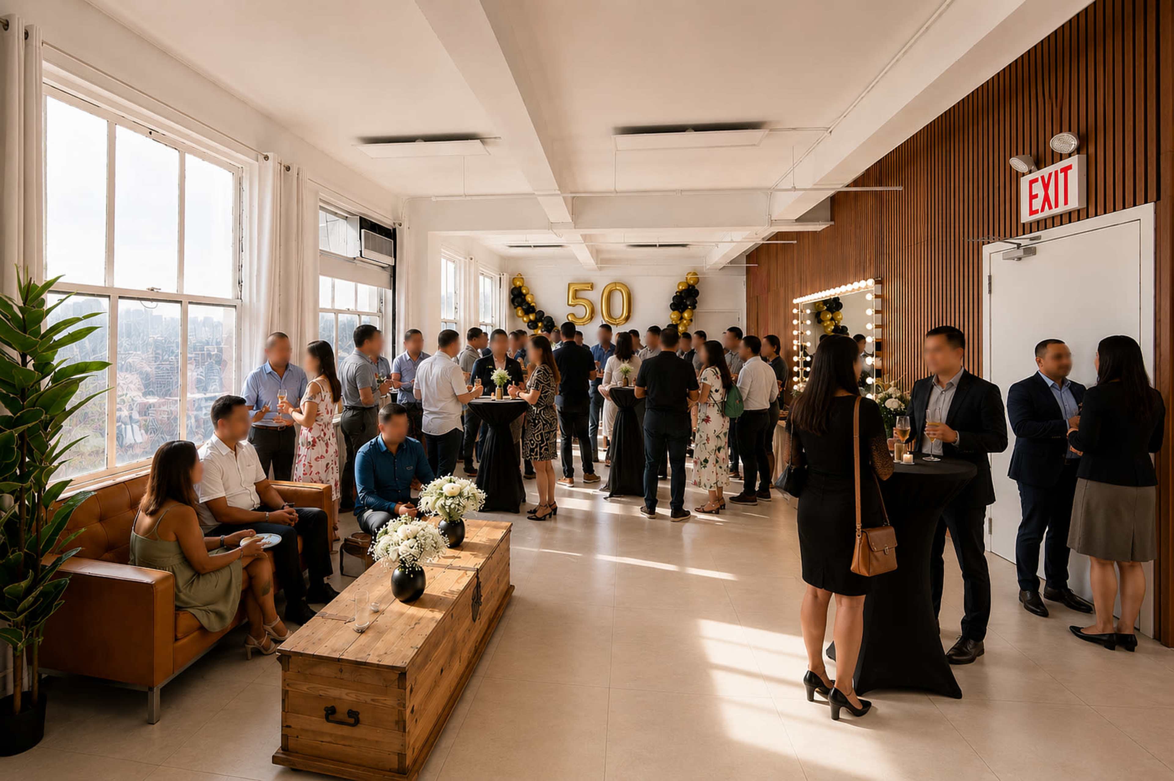 A group of people gathers in a well-lit room decorated with balloons for a 50th celebration, while some guests socialize near a wooden coffee table.