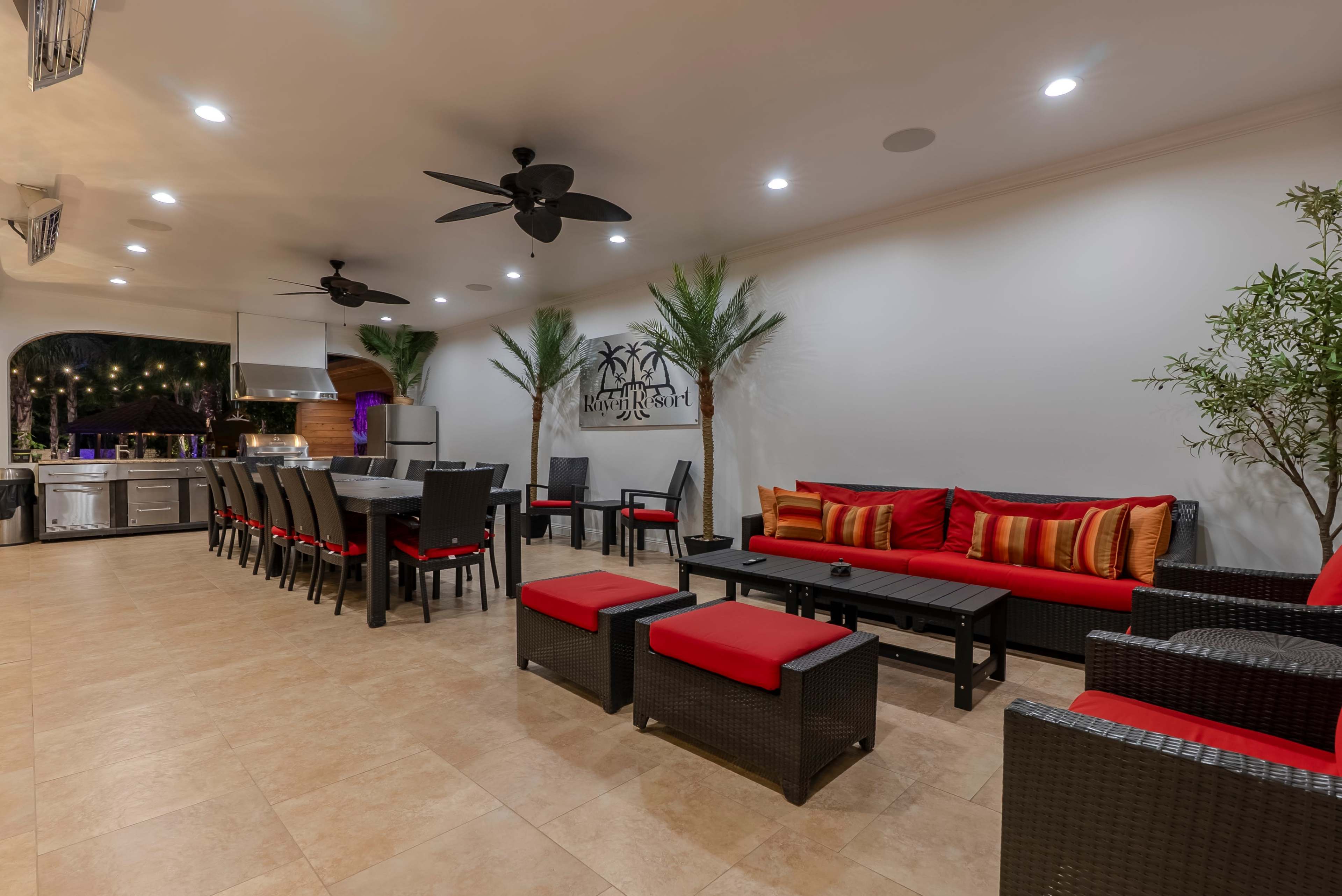 The indoor space features a seating area with red cushions, a dining table, and a kitchen equipped with modern appliances.