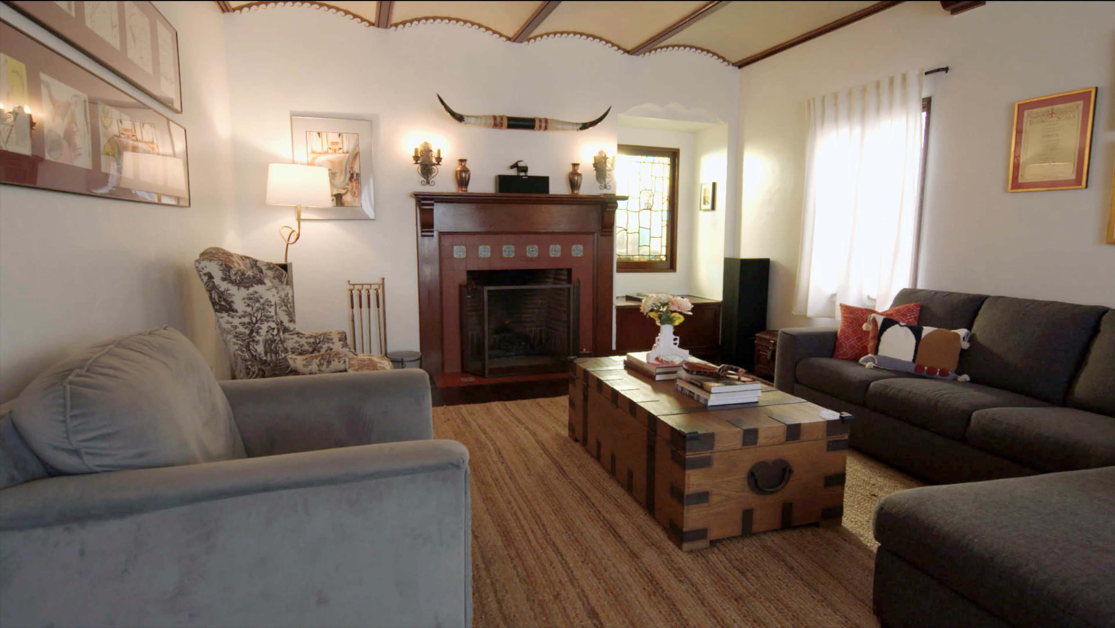 A living room features a fireplace surrounded by two sofas, a coffee table, and decor on the walls.