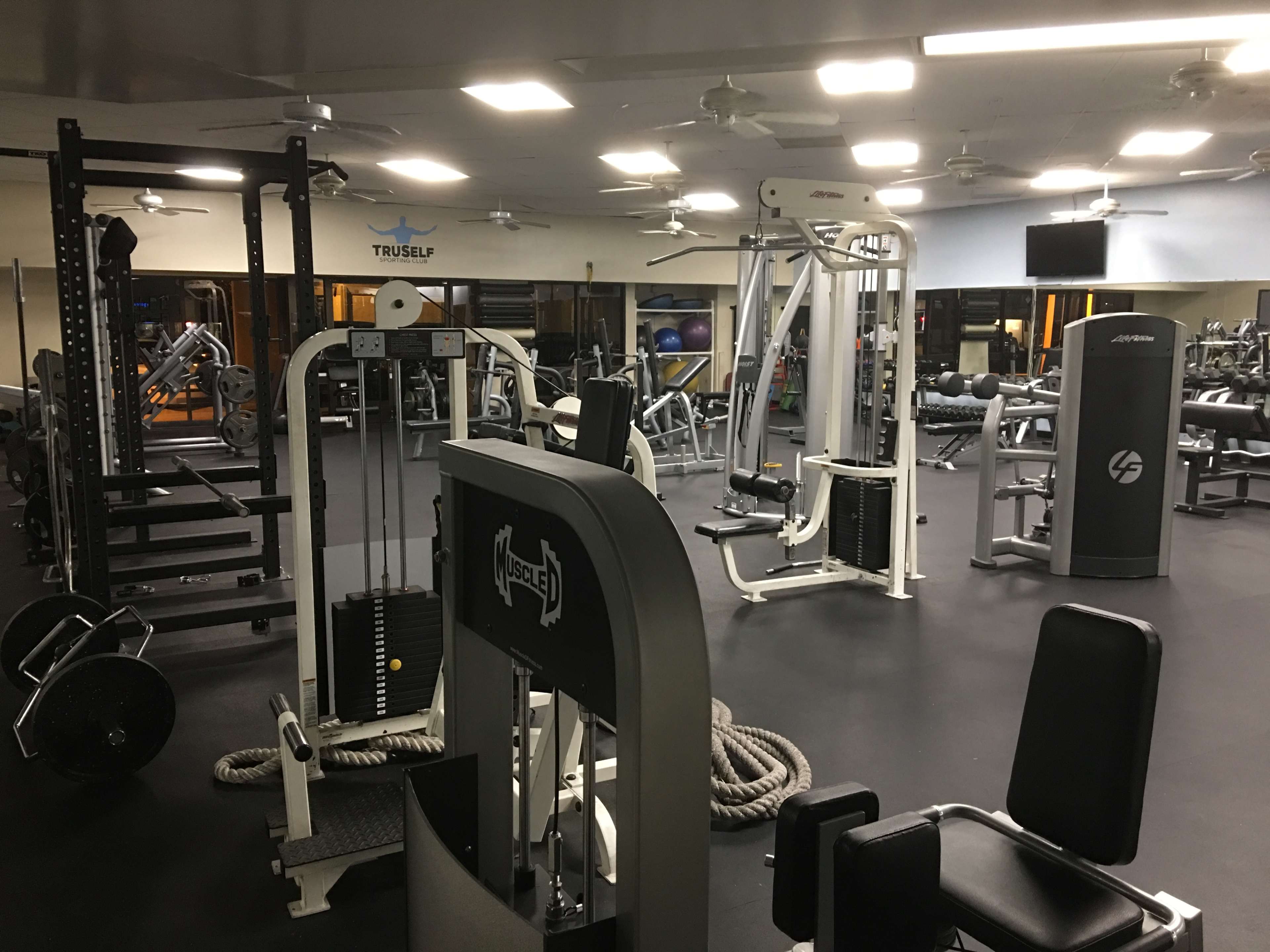 A well-equipped gym with various workout machines, weights, and fitness equipment arranged in an open space.
