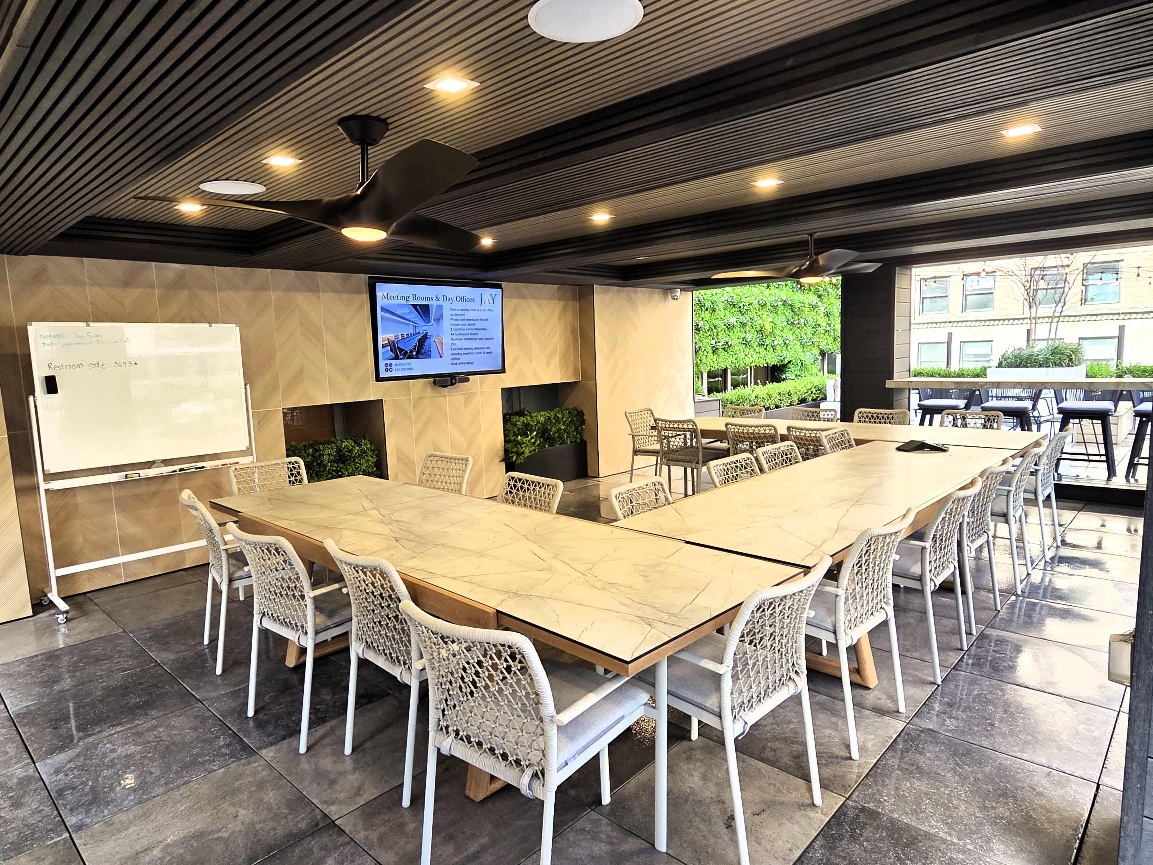The image shows a modern conference room with a long marble table, white chairs, and a large screen displaying information on a wall.