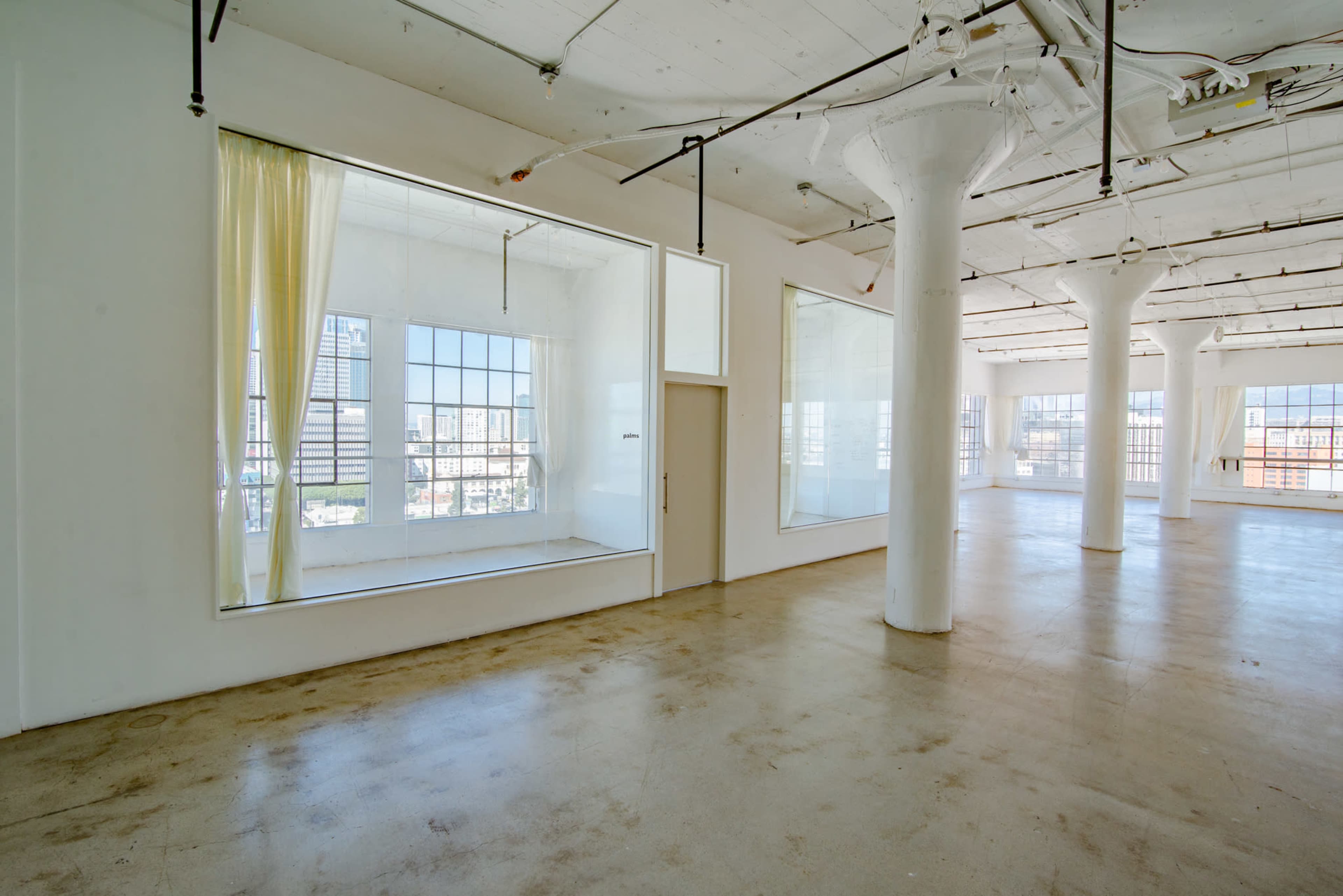 A spacious, bright interior of a modern, empty room with large windows and high ceilings.