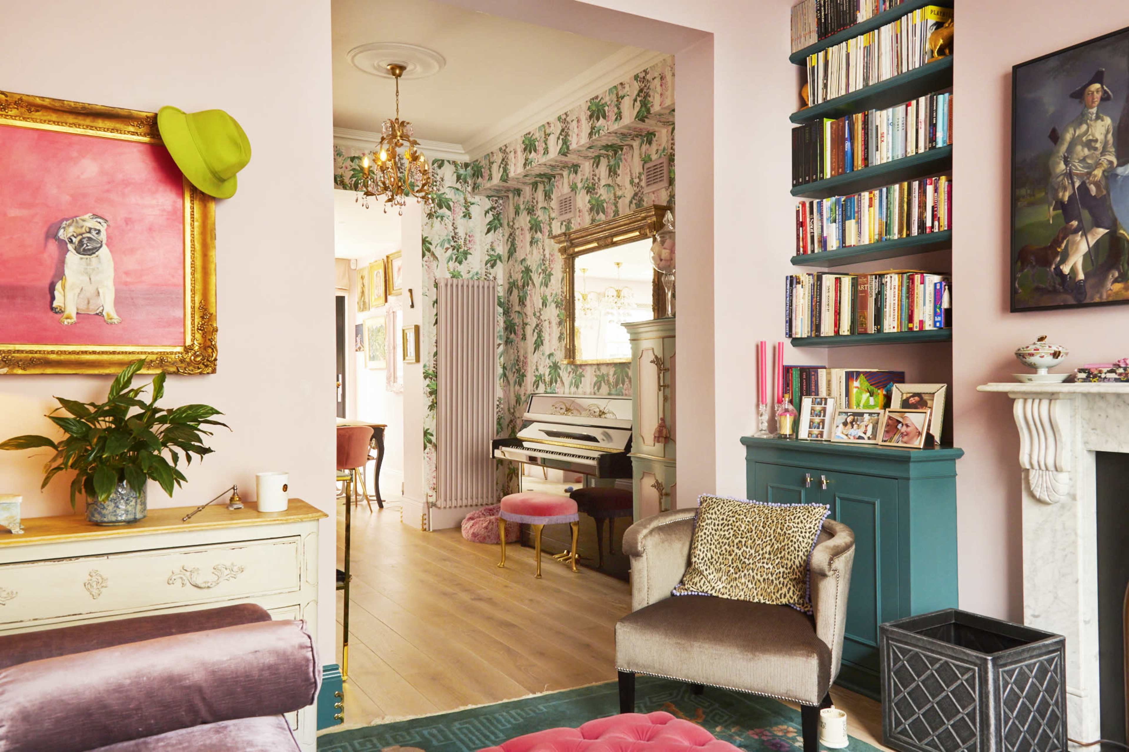 A stylishly decorated living room featuring a pink color scheme, a piano, a bookshelf, and a framed painting of a dog.