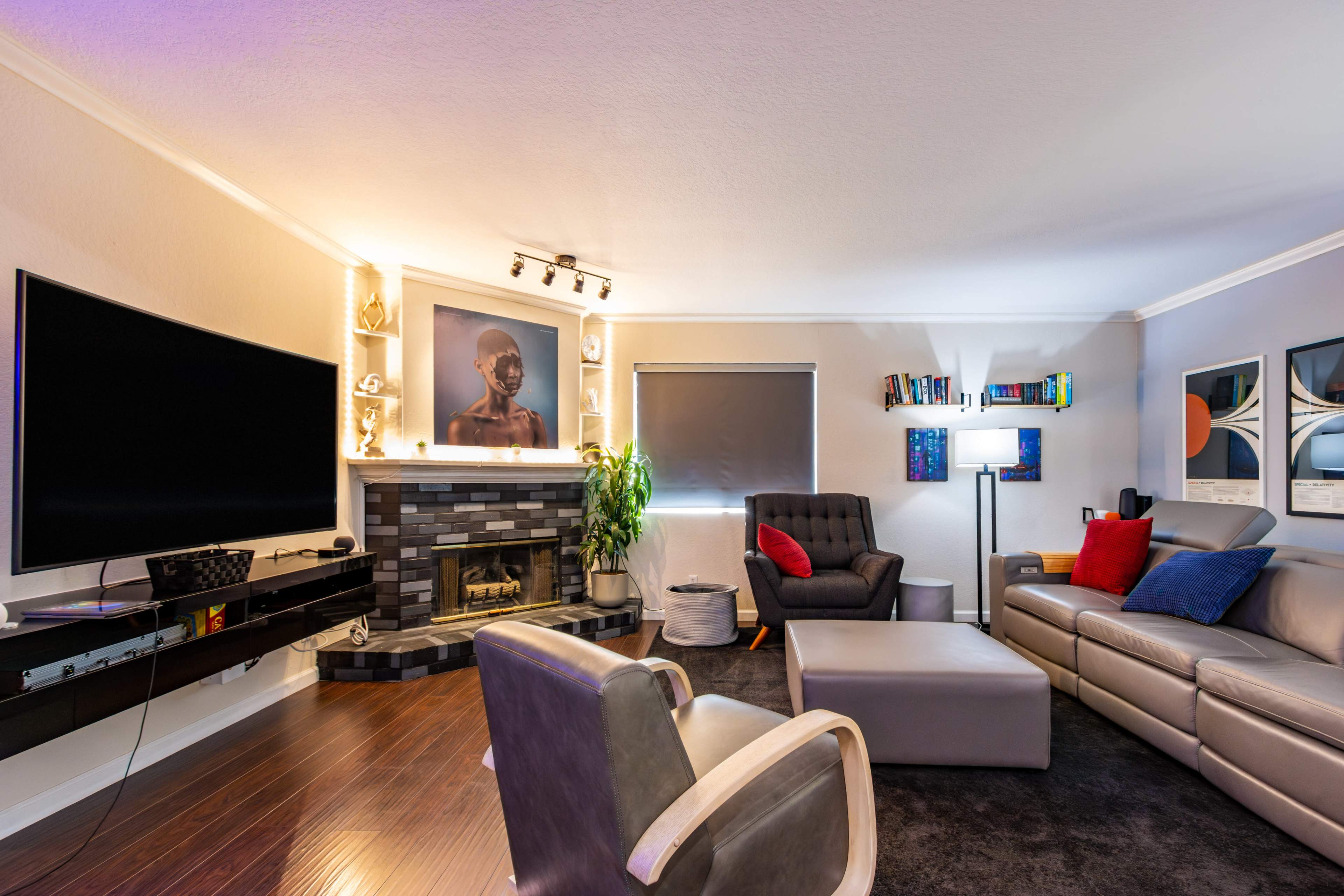 A modern living room featuring a large television, a fireplace, a sectional sofa, and various decorative elements.