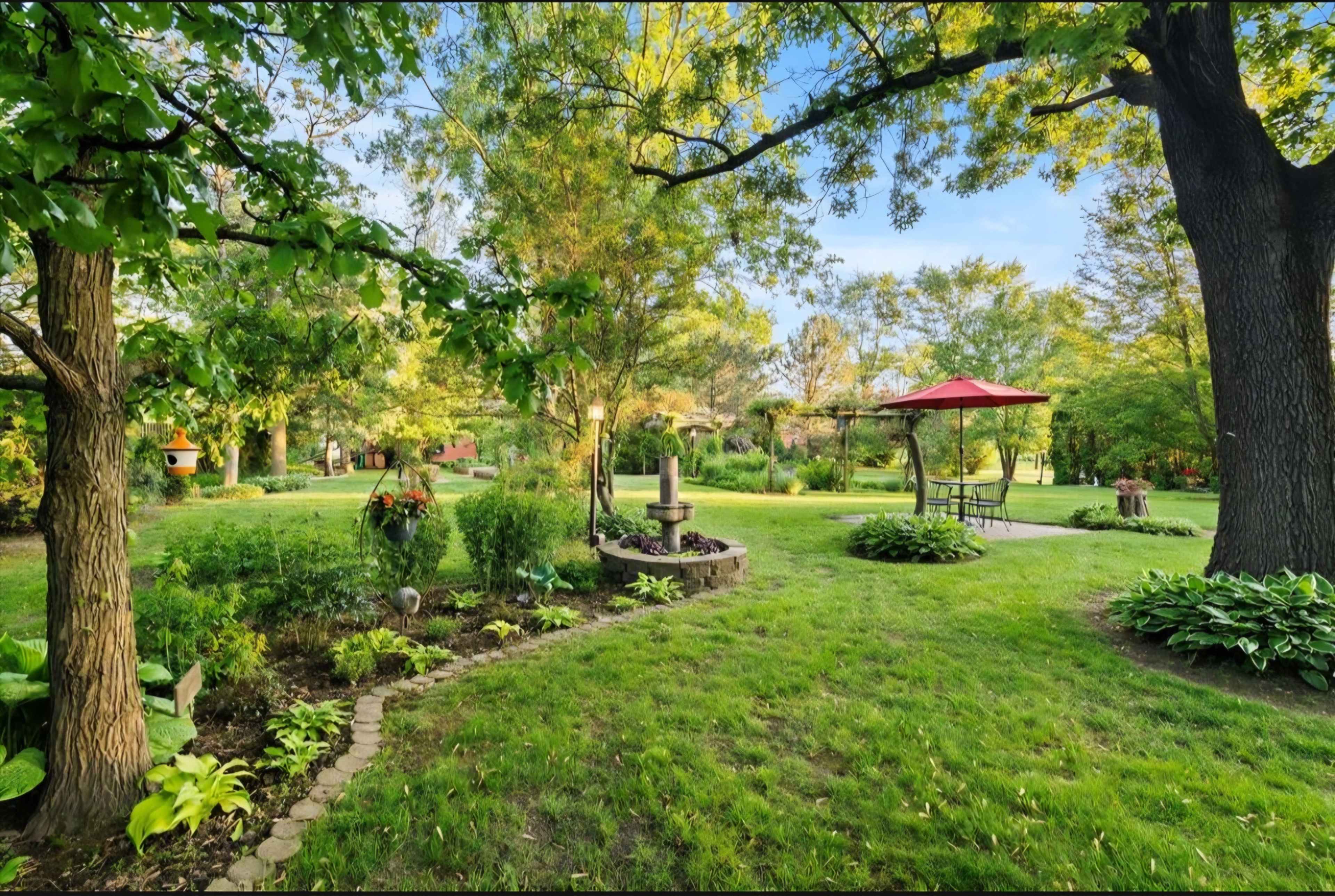 The image shows a well-maintained garden featuring lush green grass, decorative plants, a stone pathway, and a gazebo with a red roof.