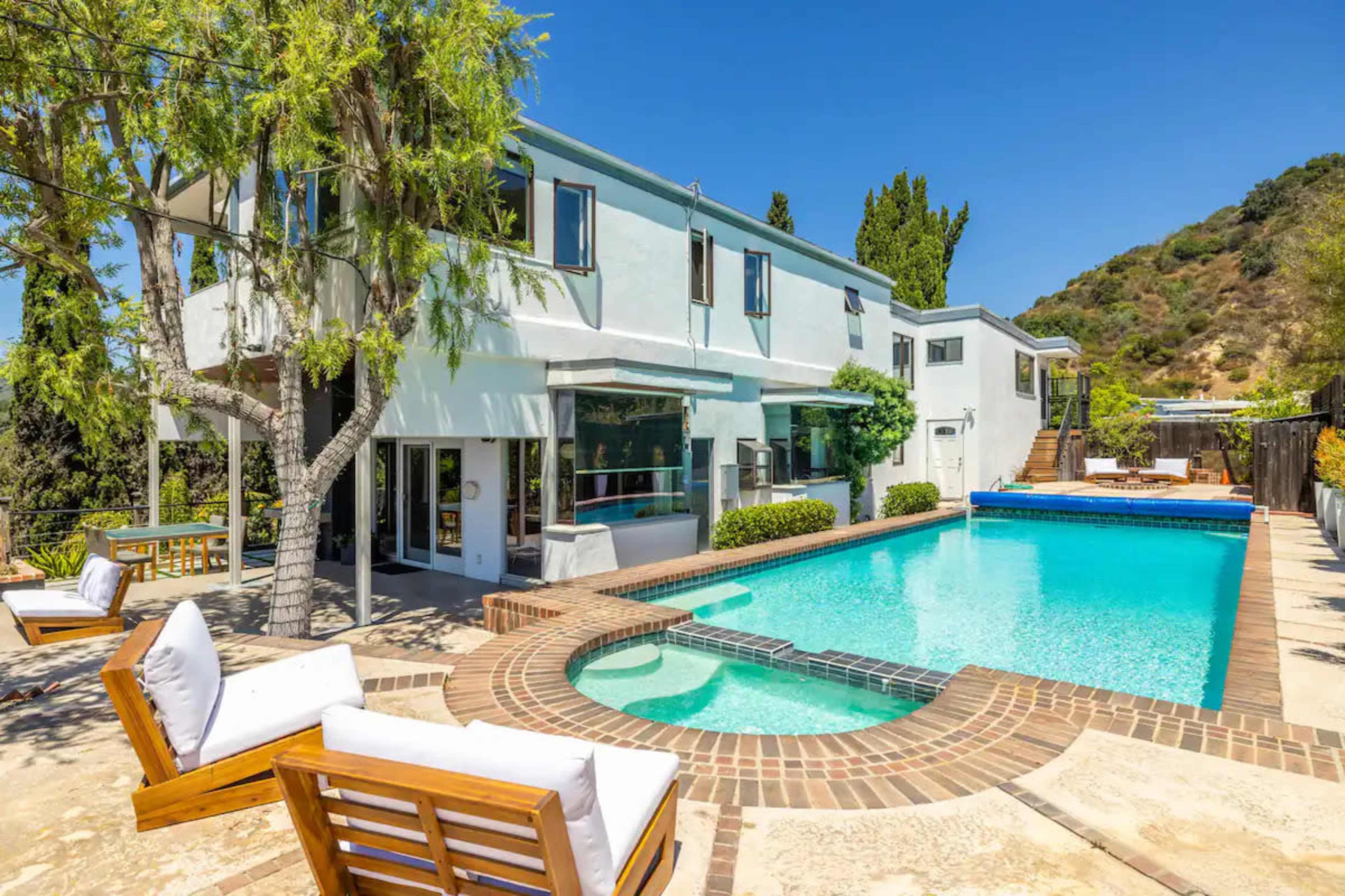 A modern house with an inviting swimming pool surrounded by landscaped greenery and outdoor seating.