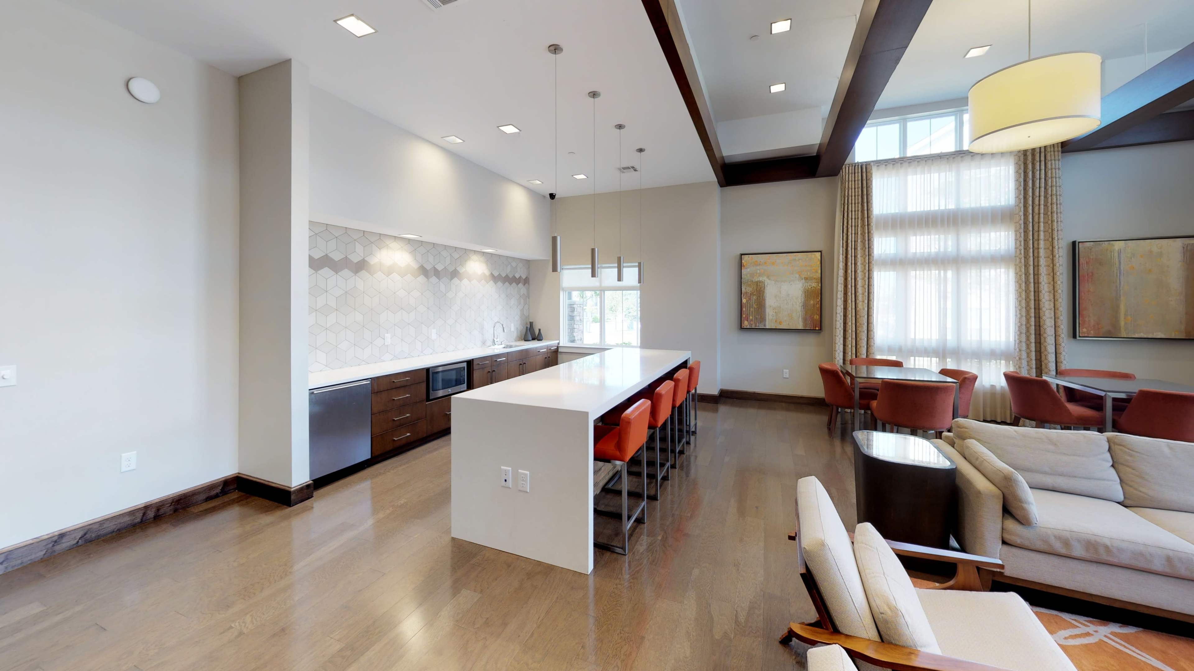 A modern interior space with a kitchen island, seating area, and large windows letting in natural light.