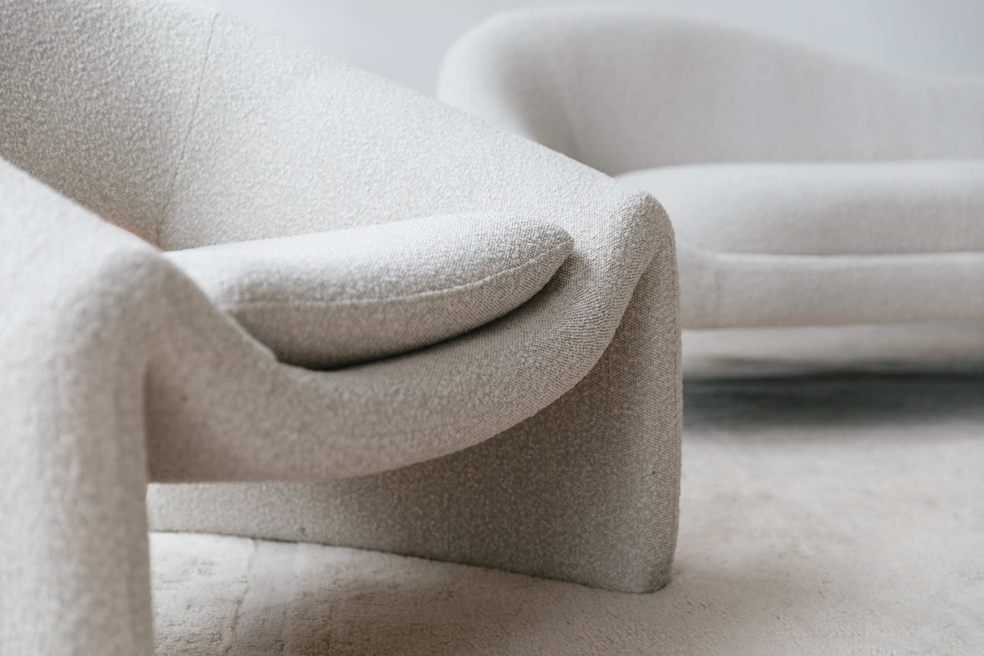 Two modern, sculptural couches with curved lines and a textured light-colored fabric.