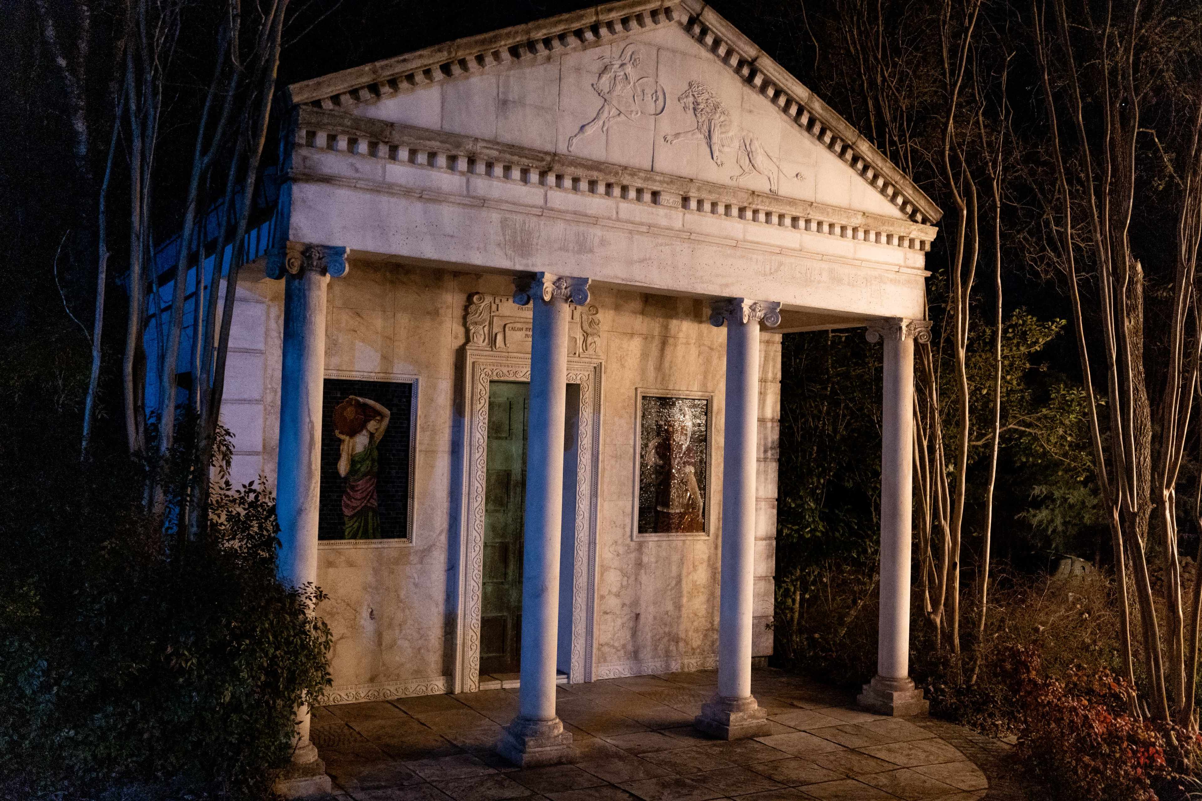 A classic-style temple structure with four columns, set in a dimly lit environment surrounded by trees.