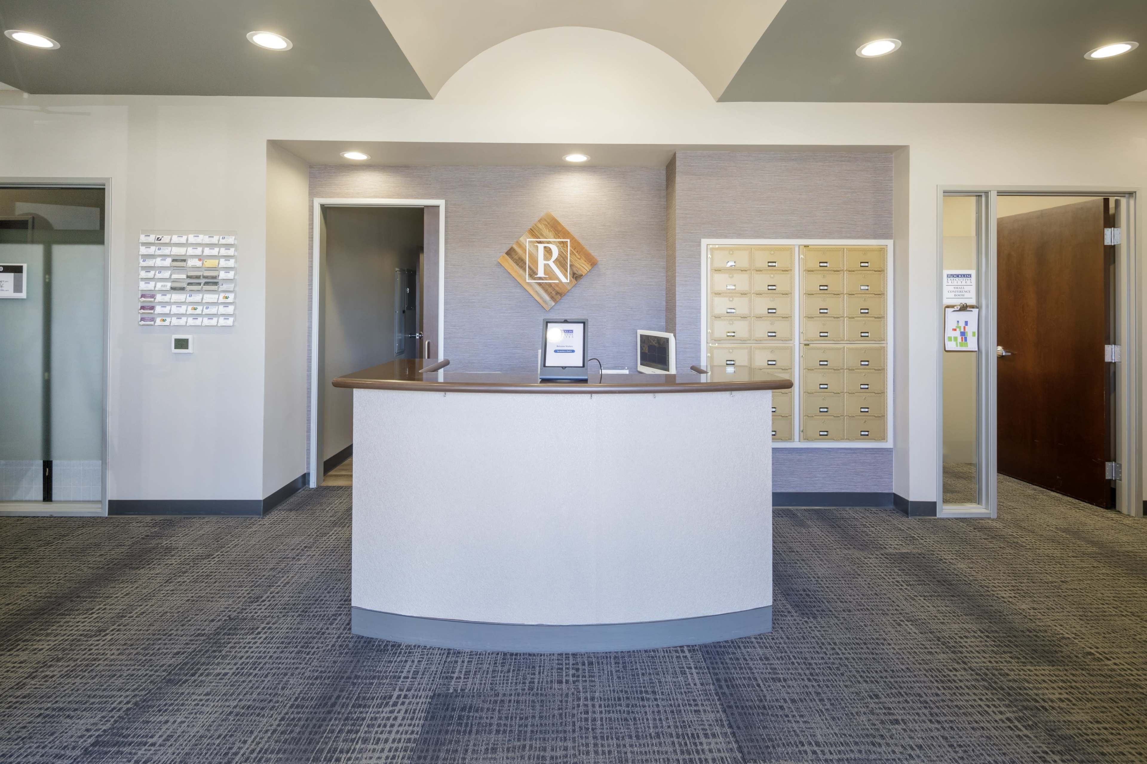 A reception area with a curved front desk, mailboxes on the wall, and two doors leading to separate rooms.