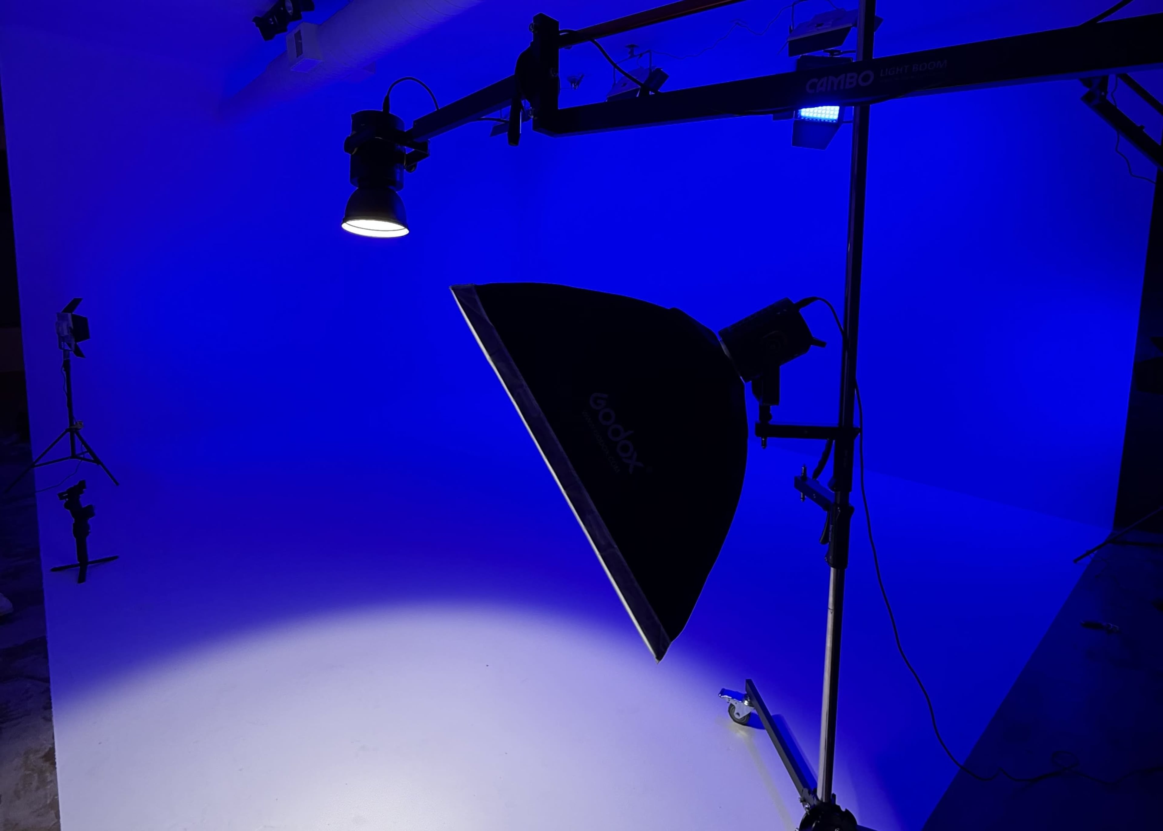 A lighting setup featuring a blue background with a softbox and additional light sources is positioned on a studio stand.