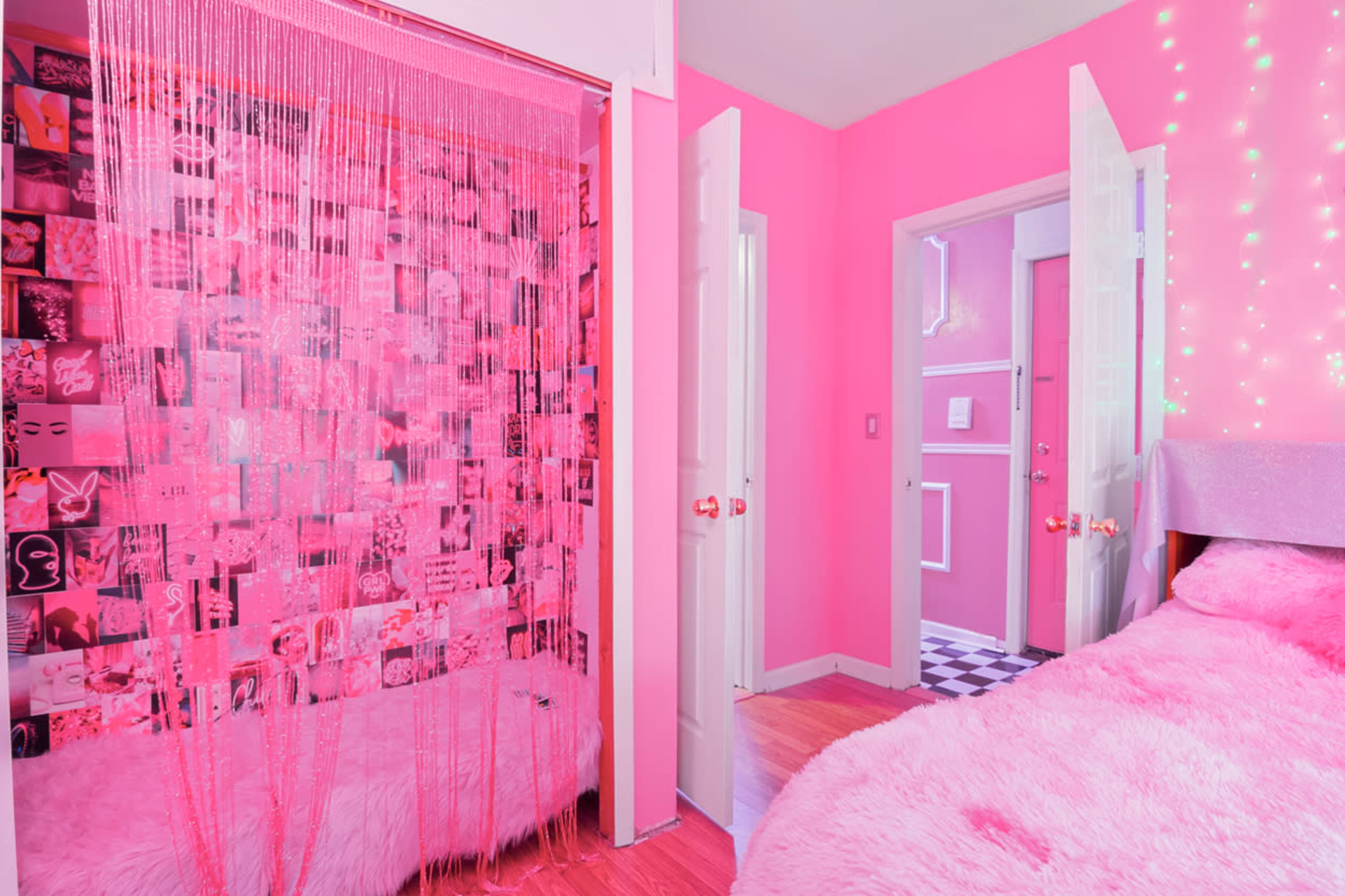 A room with pink walls, a bed covered in pink fur, and a curtain made of strings hanging between two doors adorned with photographs.