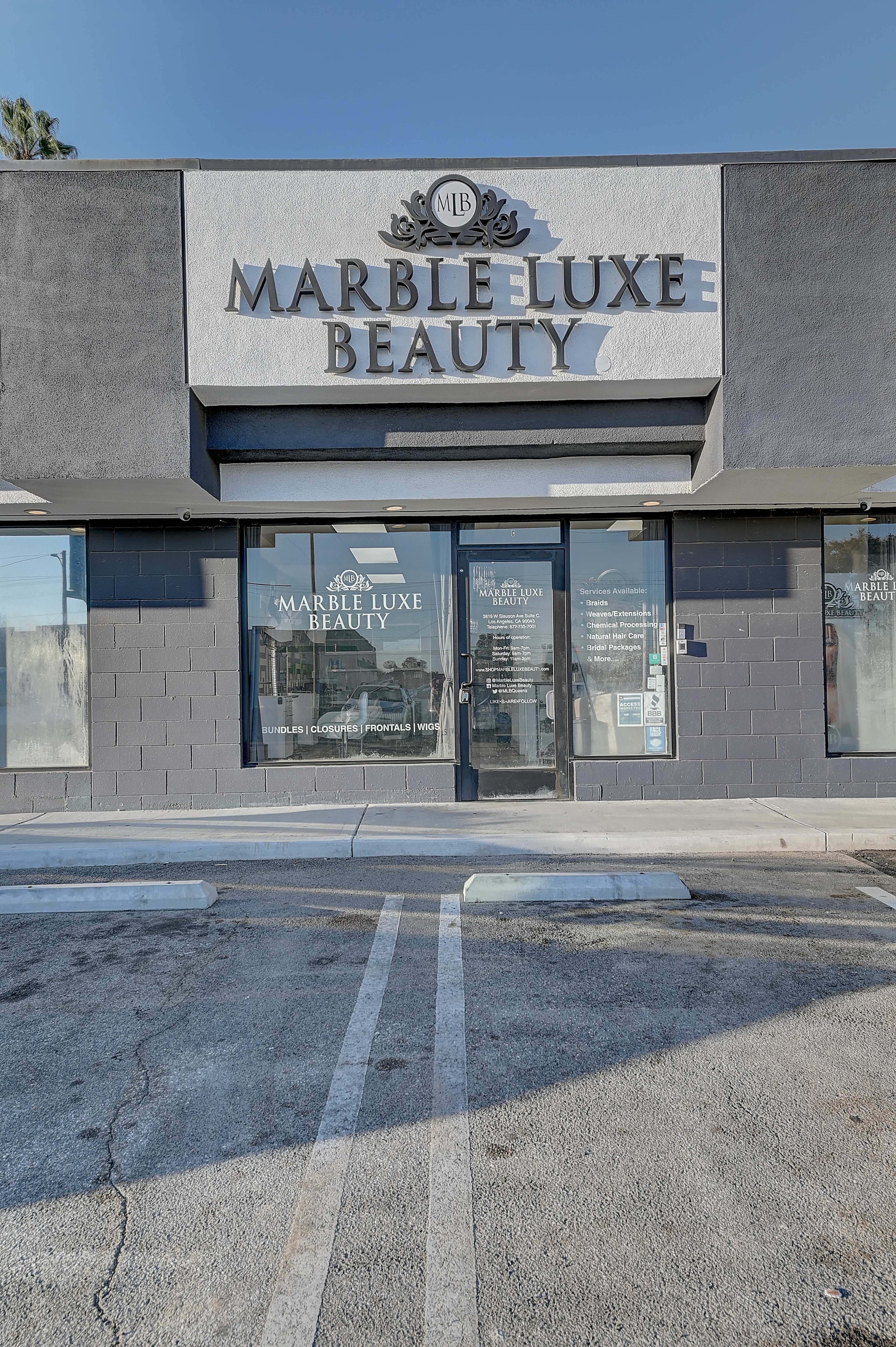 The storefront of Marble Luxe Beauty features a sign with the business name and is situated in a parking lot.