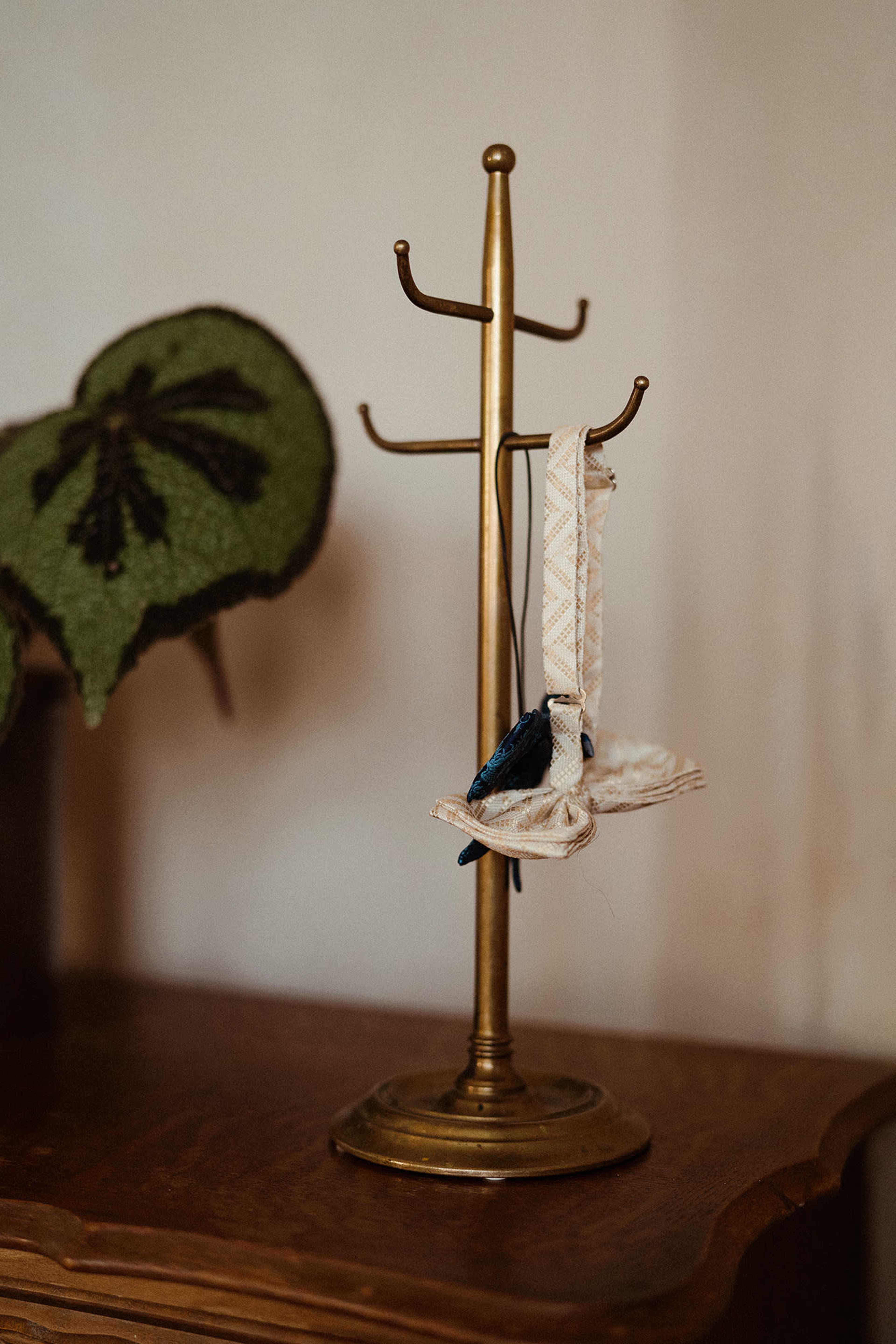A brass display stand holds a pair of white shoes with blue accents, positioned on a wooden surface.