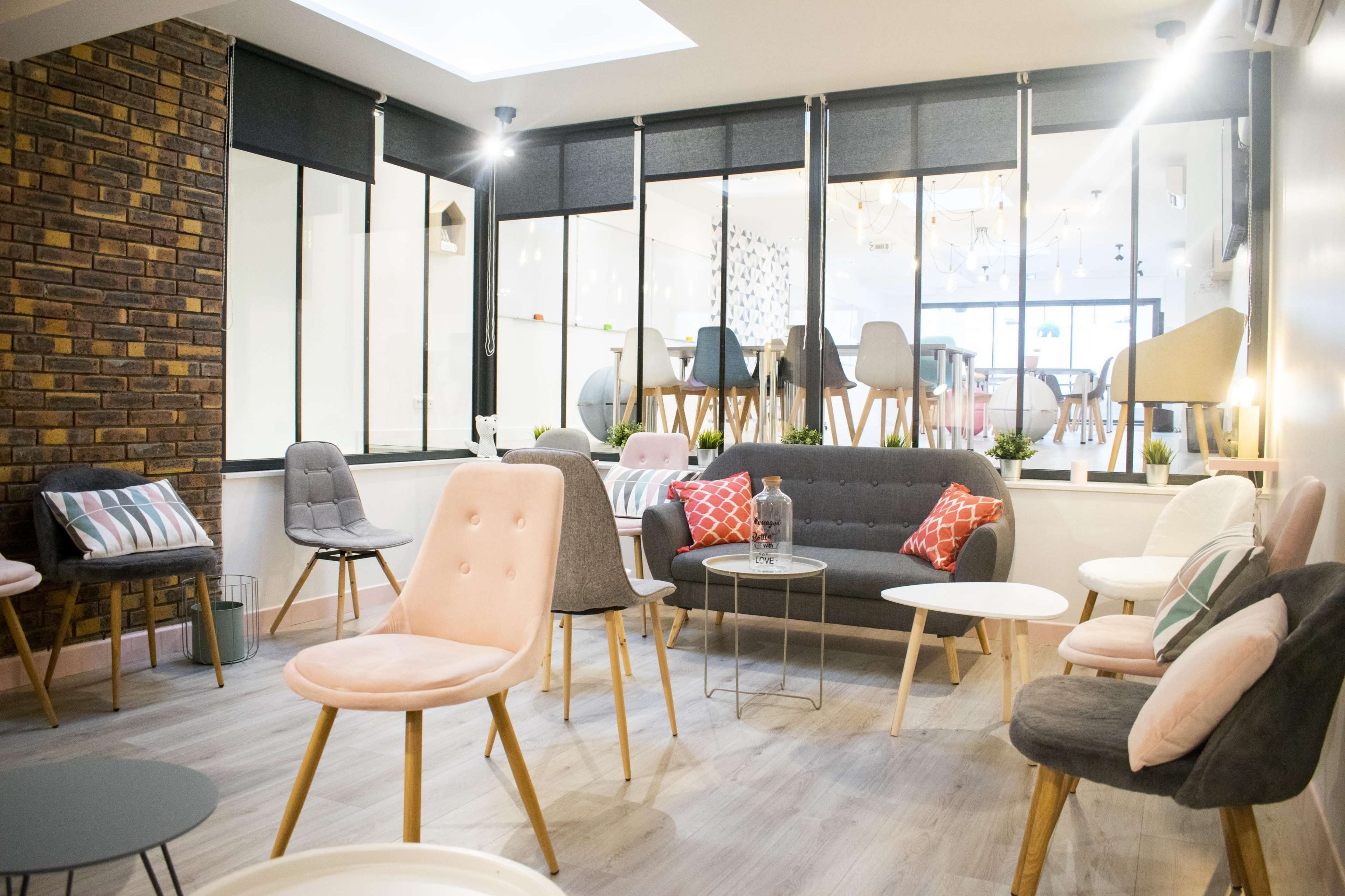 A modern seating area with various chairs and small tables arranged in a bright, spacious room.