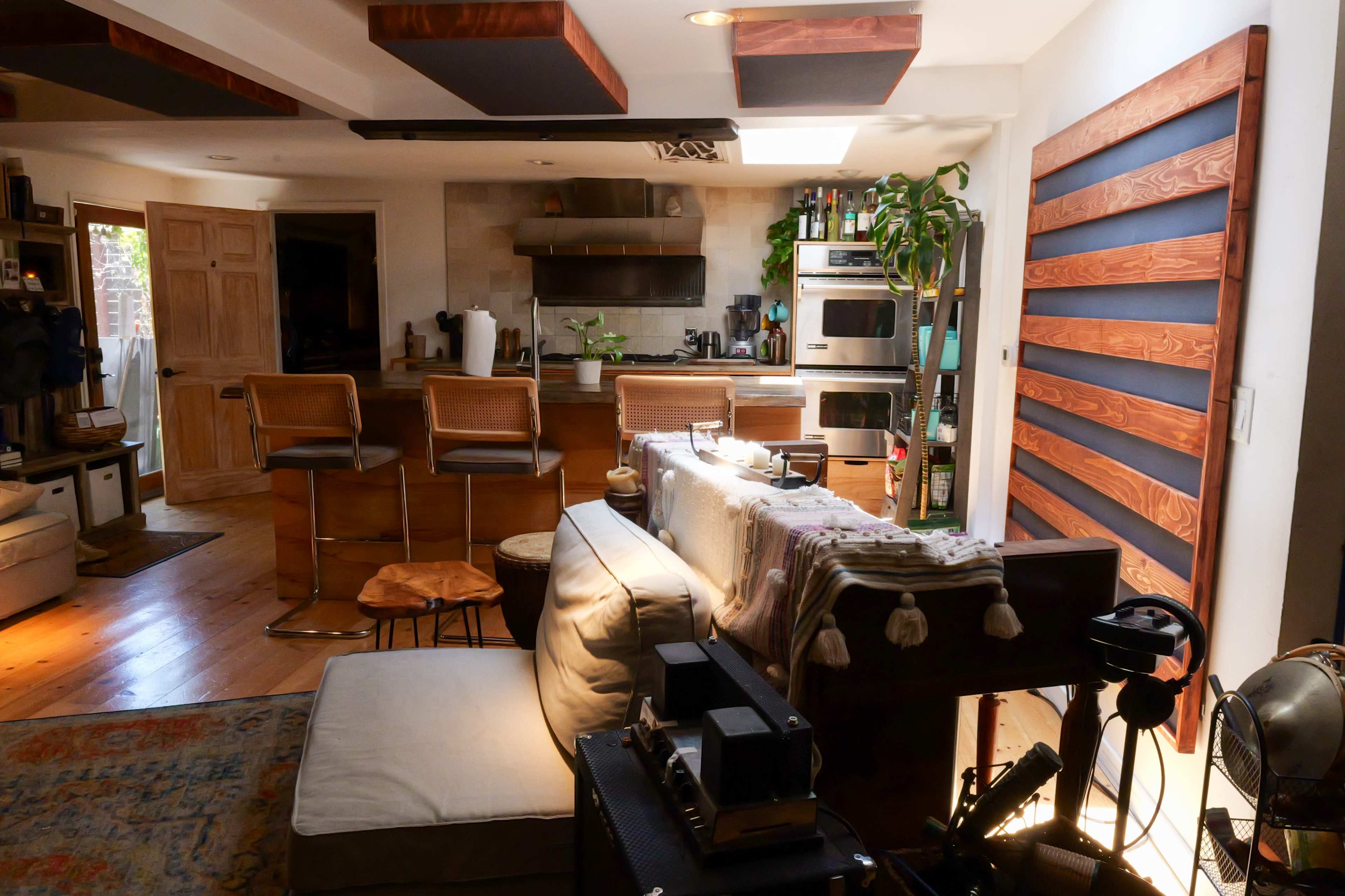 A cozy living space featuring a kitchen with bar stools, wooden accents, and a mix of furniture arrangements.